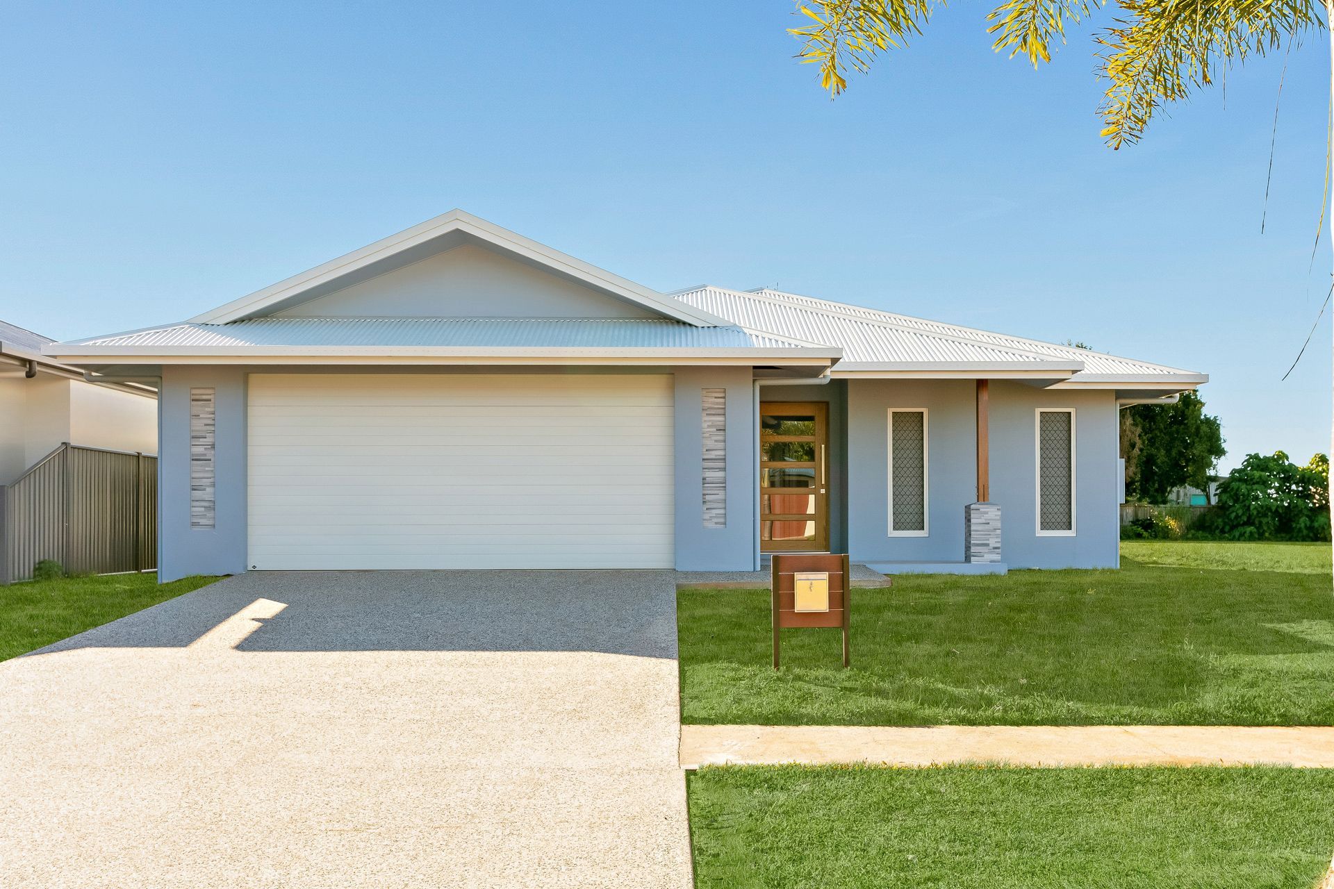 A Modern, Light Blue Single-story Suburban House With a White Garage Door — Ashlee Jones Homes in Gordonvale, QLD