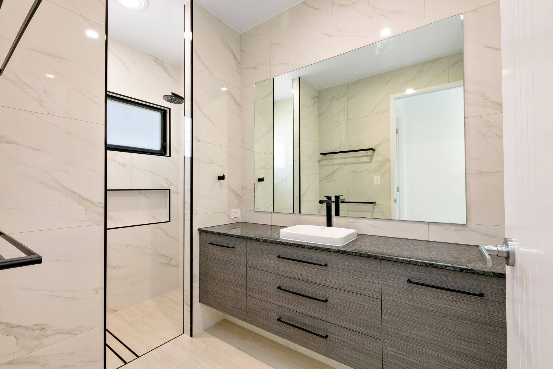 Modern Bathroom Featuring a Grey Floating Vanity, White Marble Walls — Ashlee Jones Homes in Gordonvale, QLD