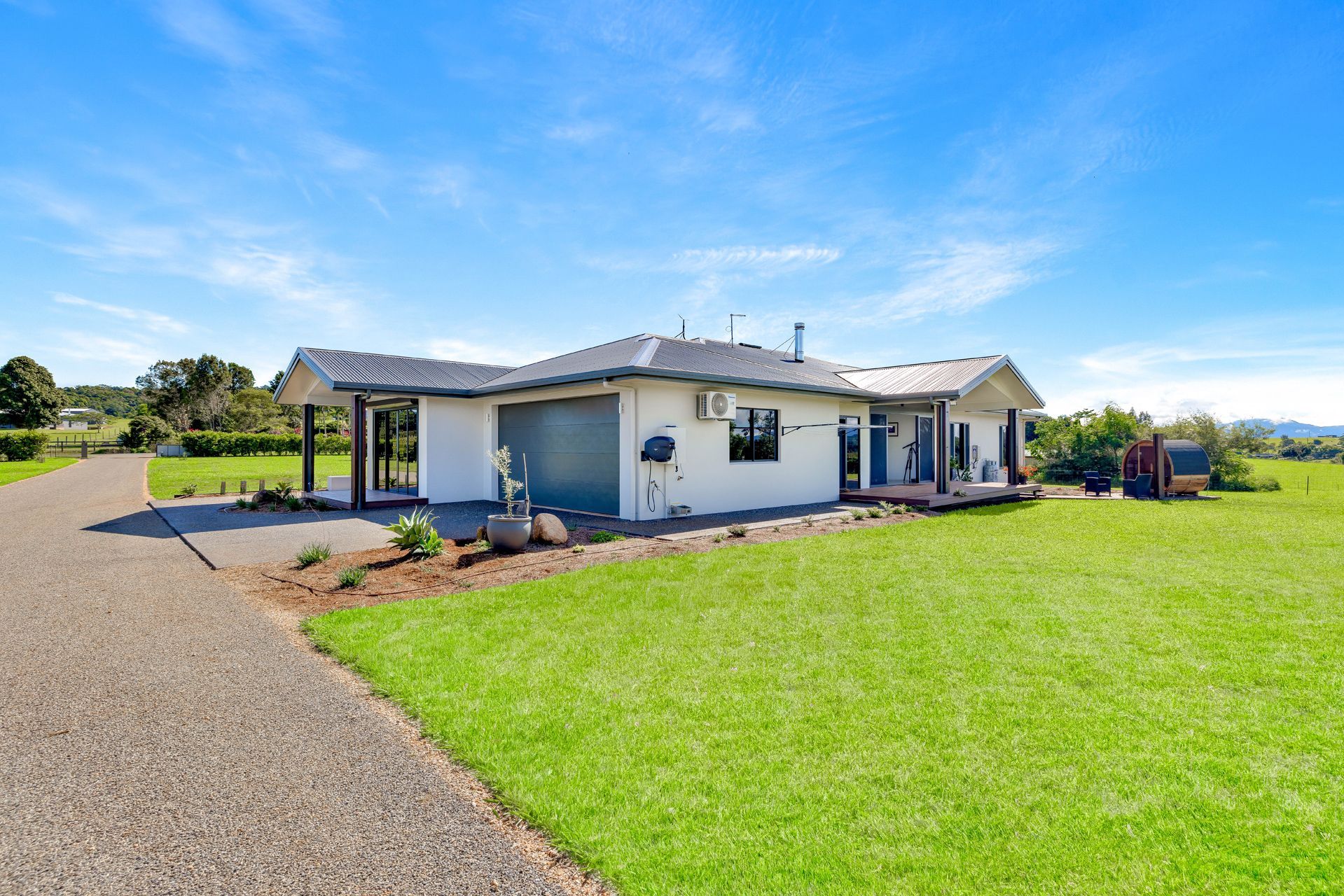 A Single-story White House With a Grey Roof and a Gravel Driveway — Ashlee Jones Homes in Gordonvale, QLD
