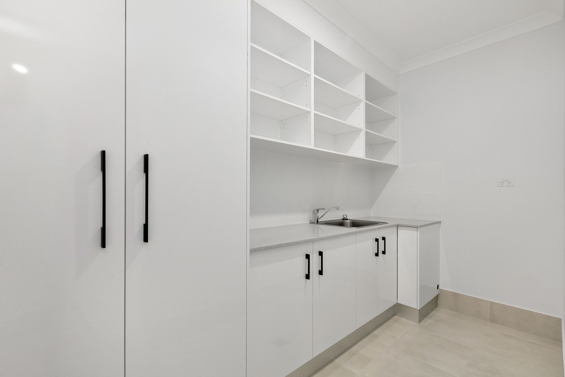 A Clean, Modern Laundry Room Featuring White Cabinetry — Ashlee Jones Homes in Gordonvale, QLD