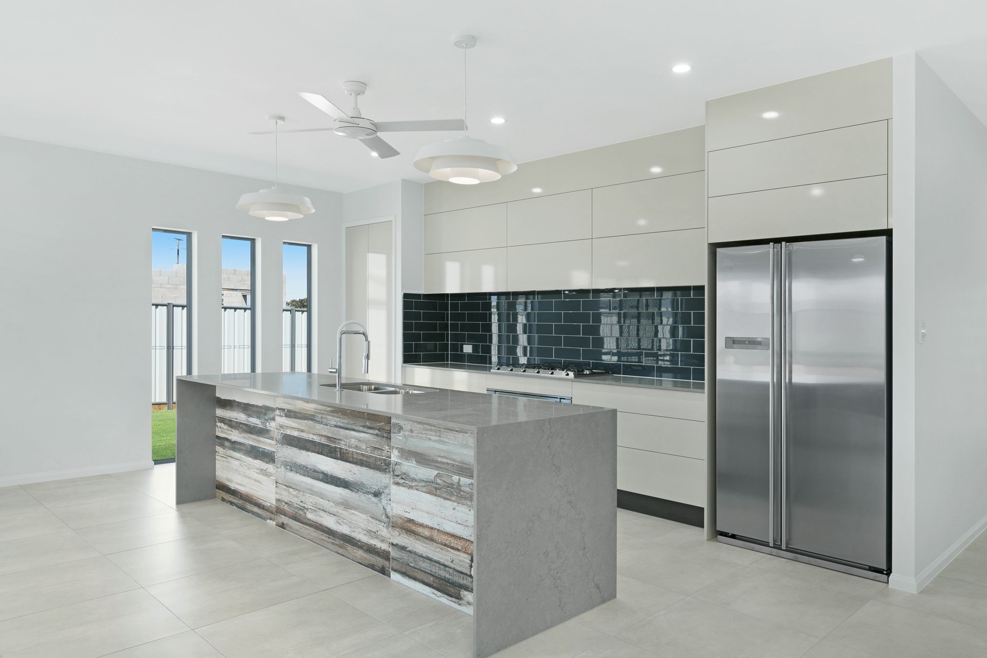 Modern Kitchen With a Gray Stone Island, Glossy Beige Cabinets — Ashlee Jones Homes in Gordonvale, QLD
