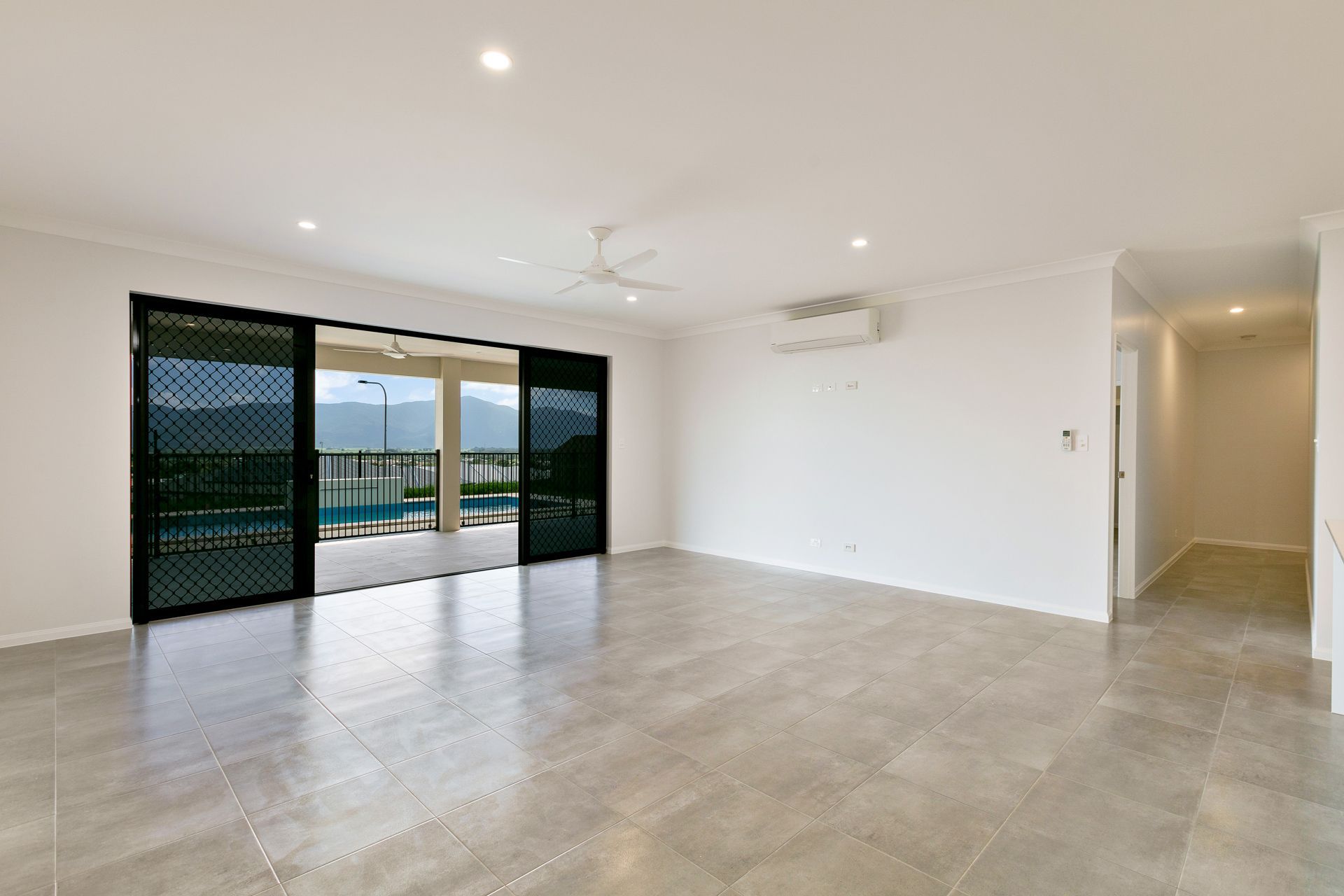 An Empty, Bright Room With Large Glass Sliding Doors — Ashlee Jones Homes in Gordonvale, QLD