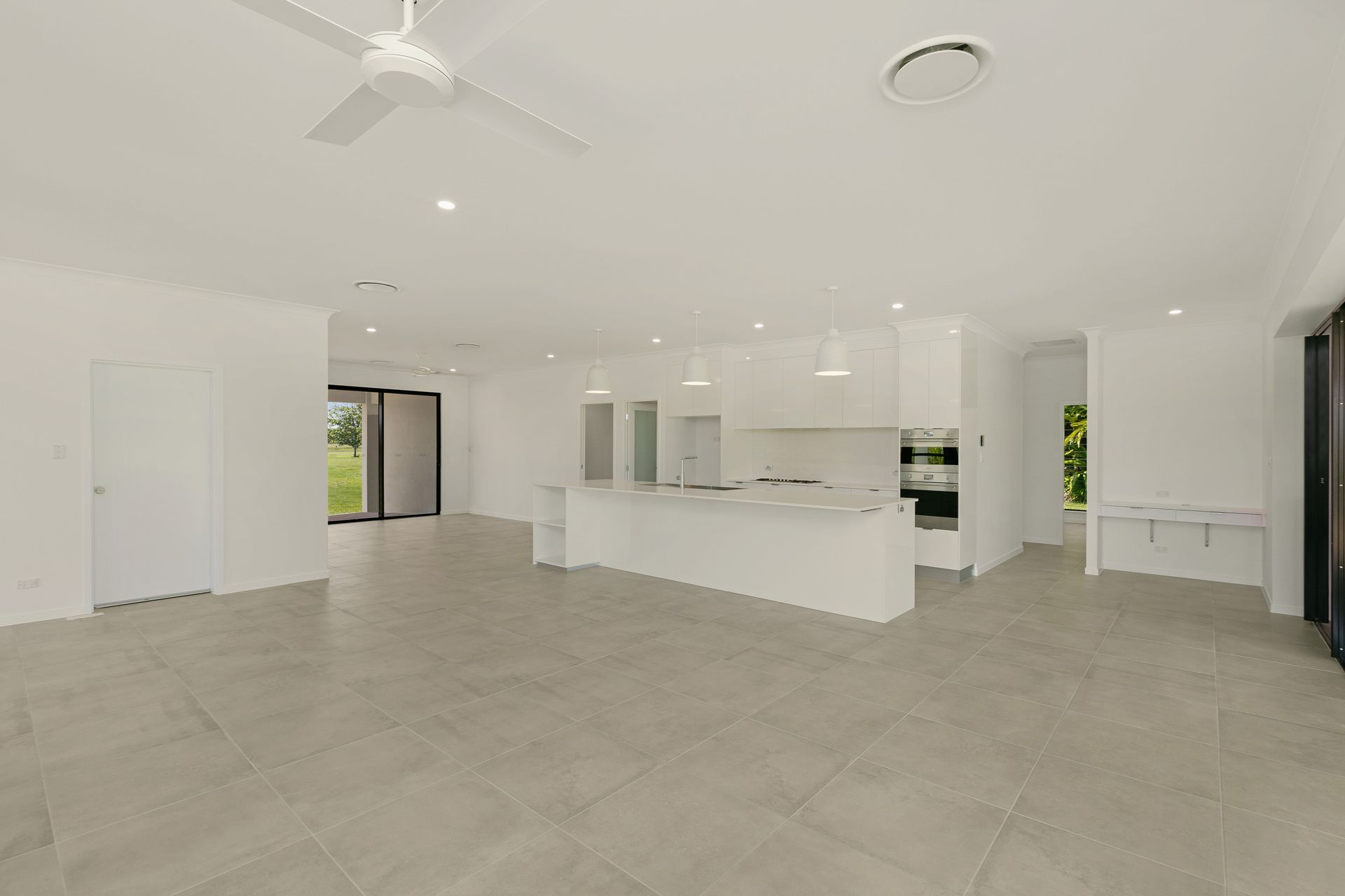 A Modern, Spacious, Open-plan Kitchen and Living Area With White Cabinetry — Ashlee Jones Homes in Gordonvale, QLD