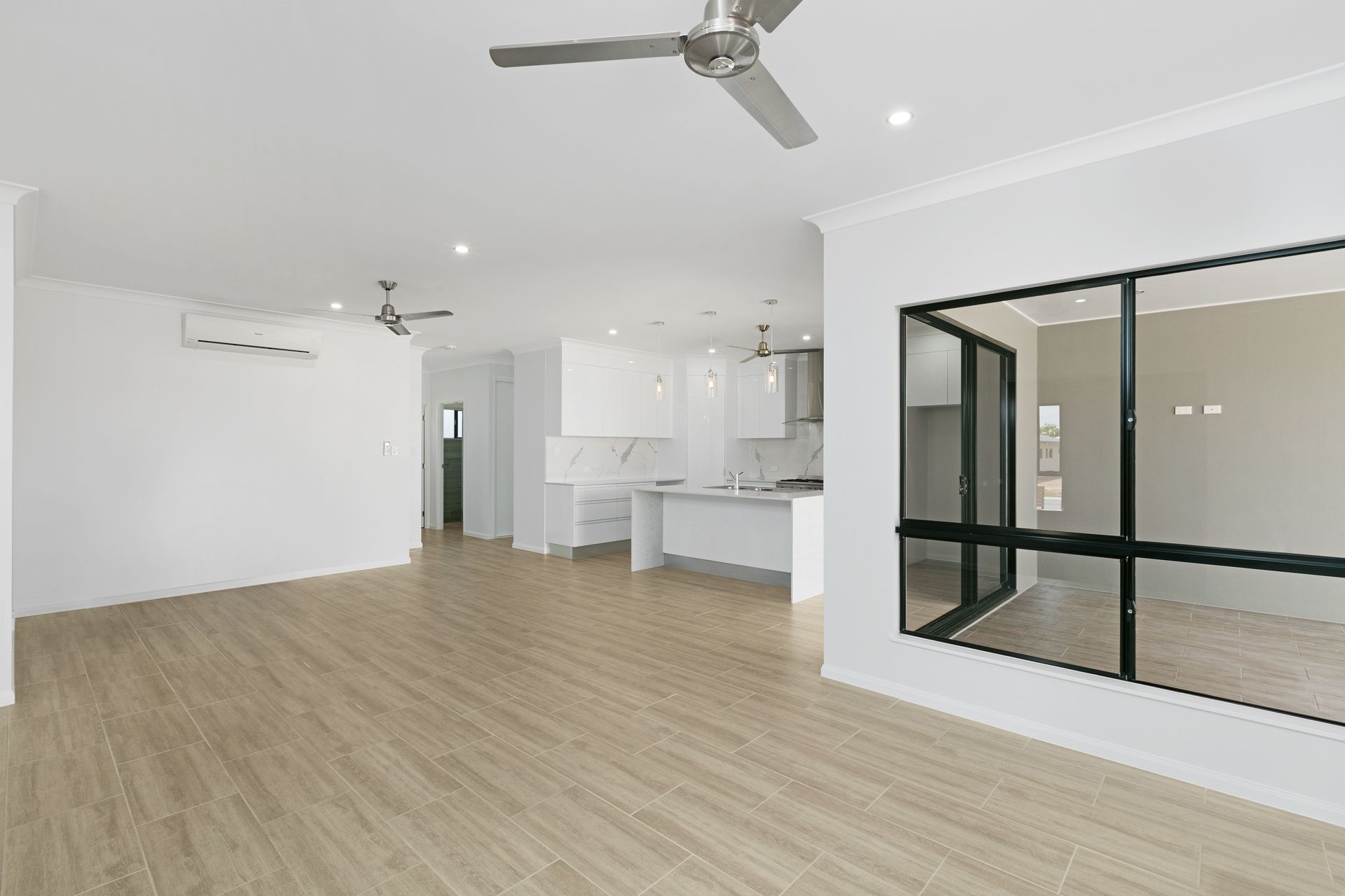 A Modern, Open-concept Living Space With Light Wood Floors — Ashlee Jones Homes in Gordonvale, QLD