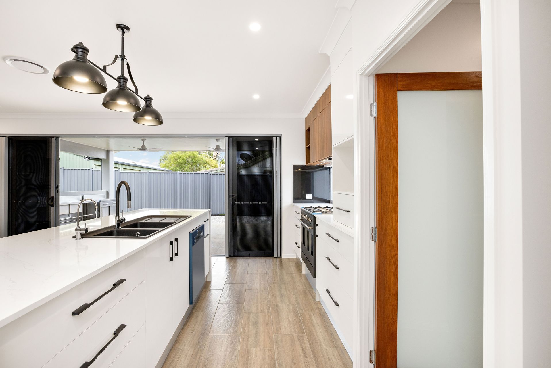 A Modern Kitchen With a White Island, Dark Faucet — Ashlee Jones Homes in Gordonvale, QLD