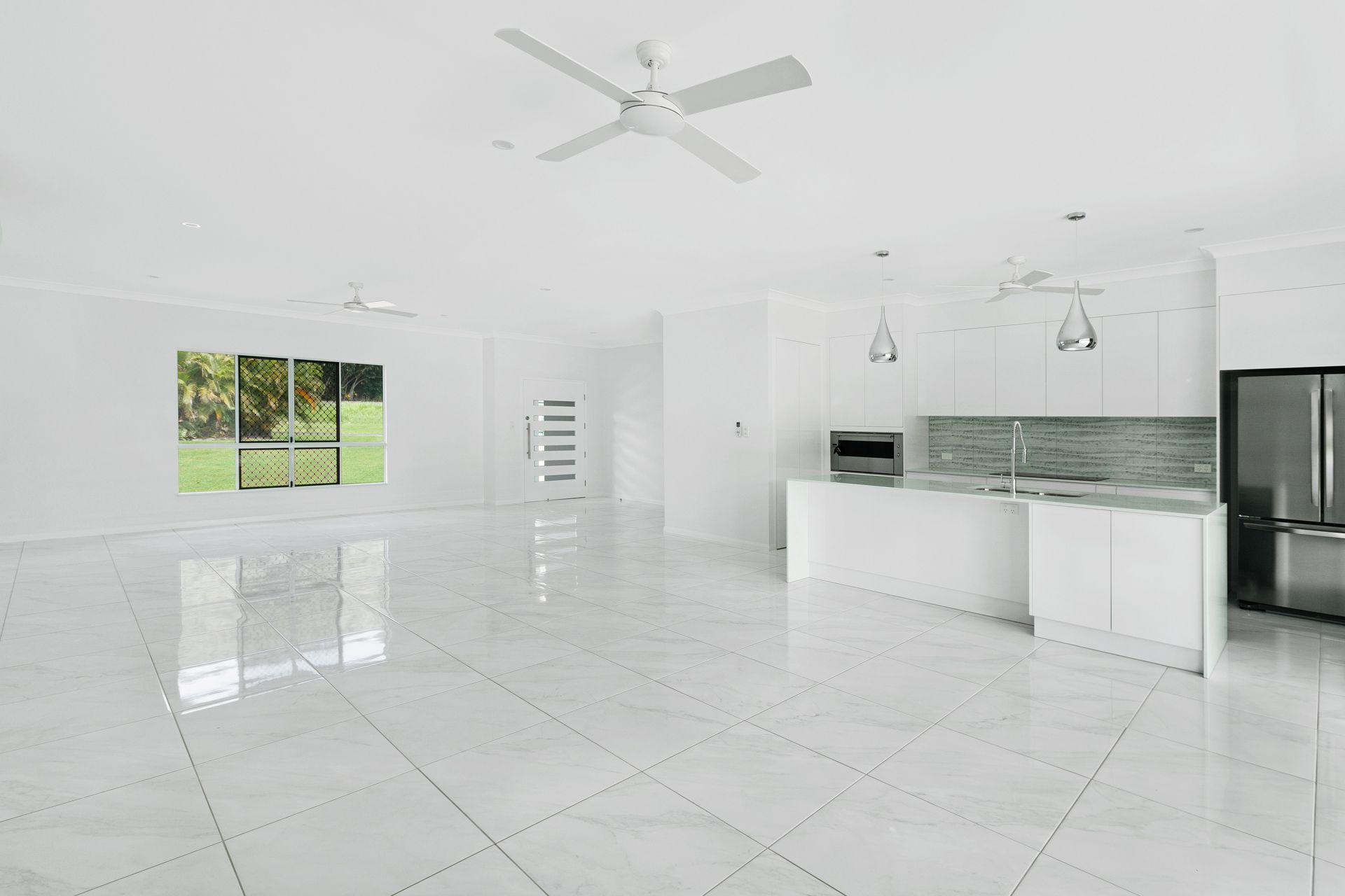 A Bright, Modern Open-plan Kitchen and Living Area Featuring White Cabinetry — Ashlee Jones Homes in Gordonvale, QLD