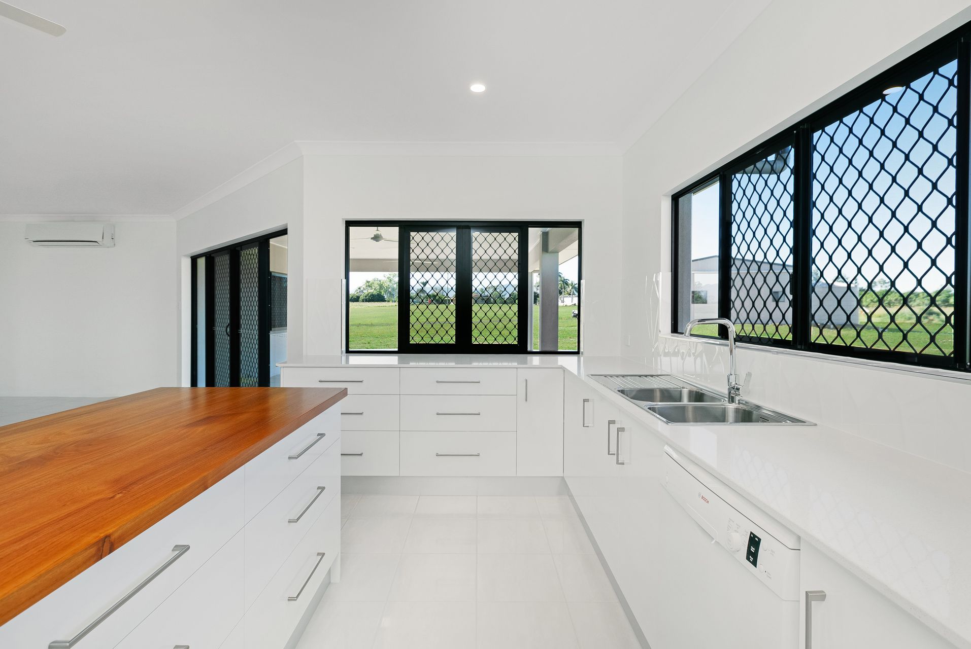 Modern Kitchen With White Cabinets, a Wooden Island Countertop — Ashlee Jones Homes in Gordonvale, QLD