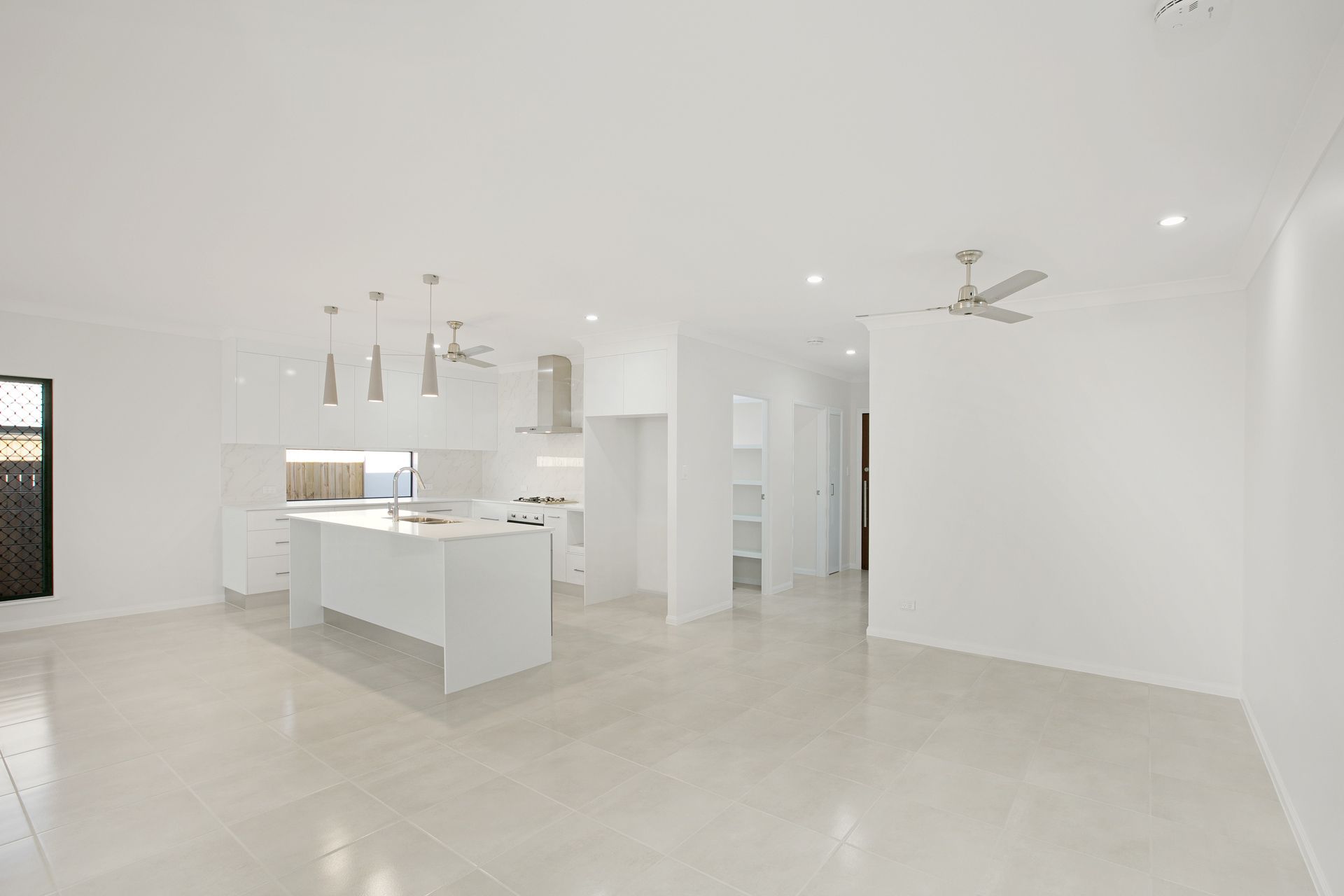 A Modern, Minimalist Open-plan Kitchen and Living Area With White Cabinetry — Ashlee Jones Homes in Gordonvale, QLD