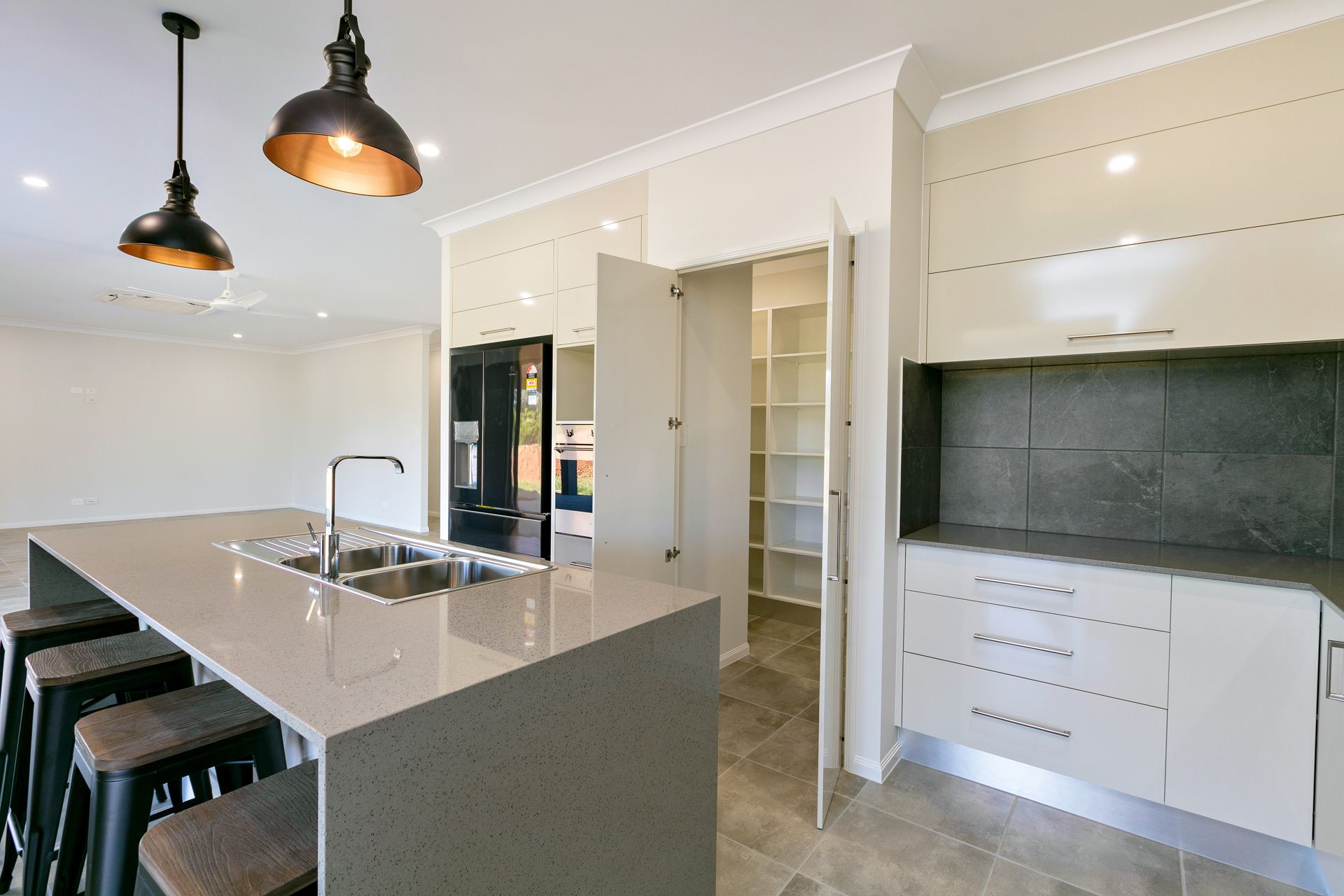 A Modern Kitchen Featuring a Stone-topped Island With Stools — Ashlee Jones Homes in Gordonvale, QLD
