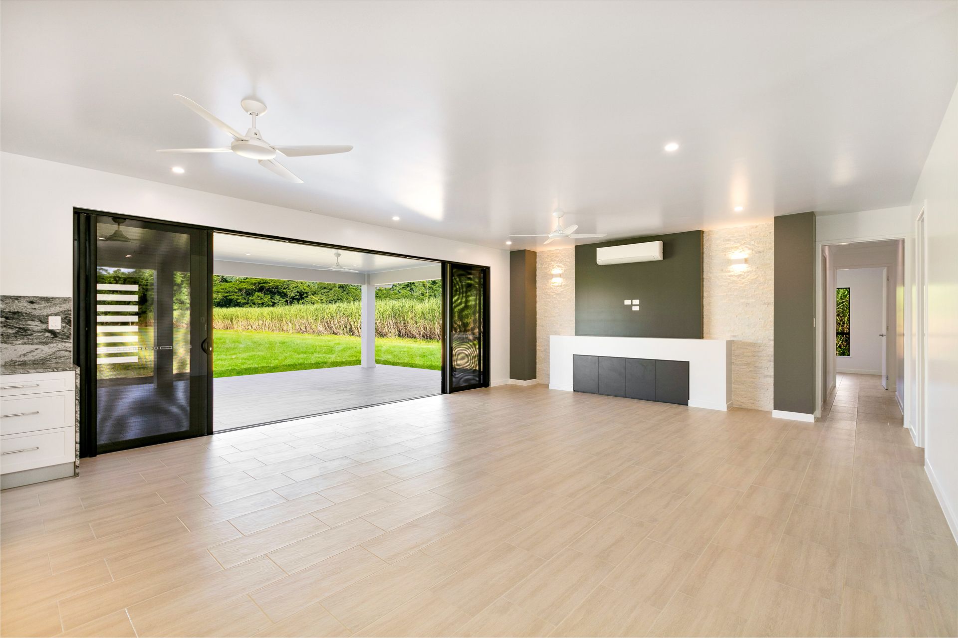 Modern, Empty Living Room With Light Wood Floors, Large Sliding Glass Doors — Ashlee Jones Homes in Gordonvale, QLD