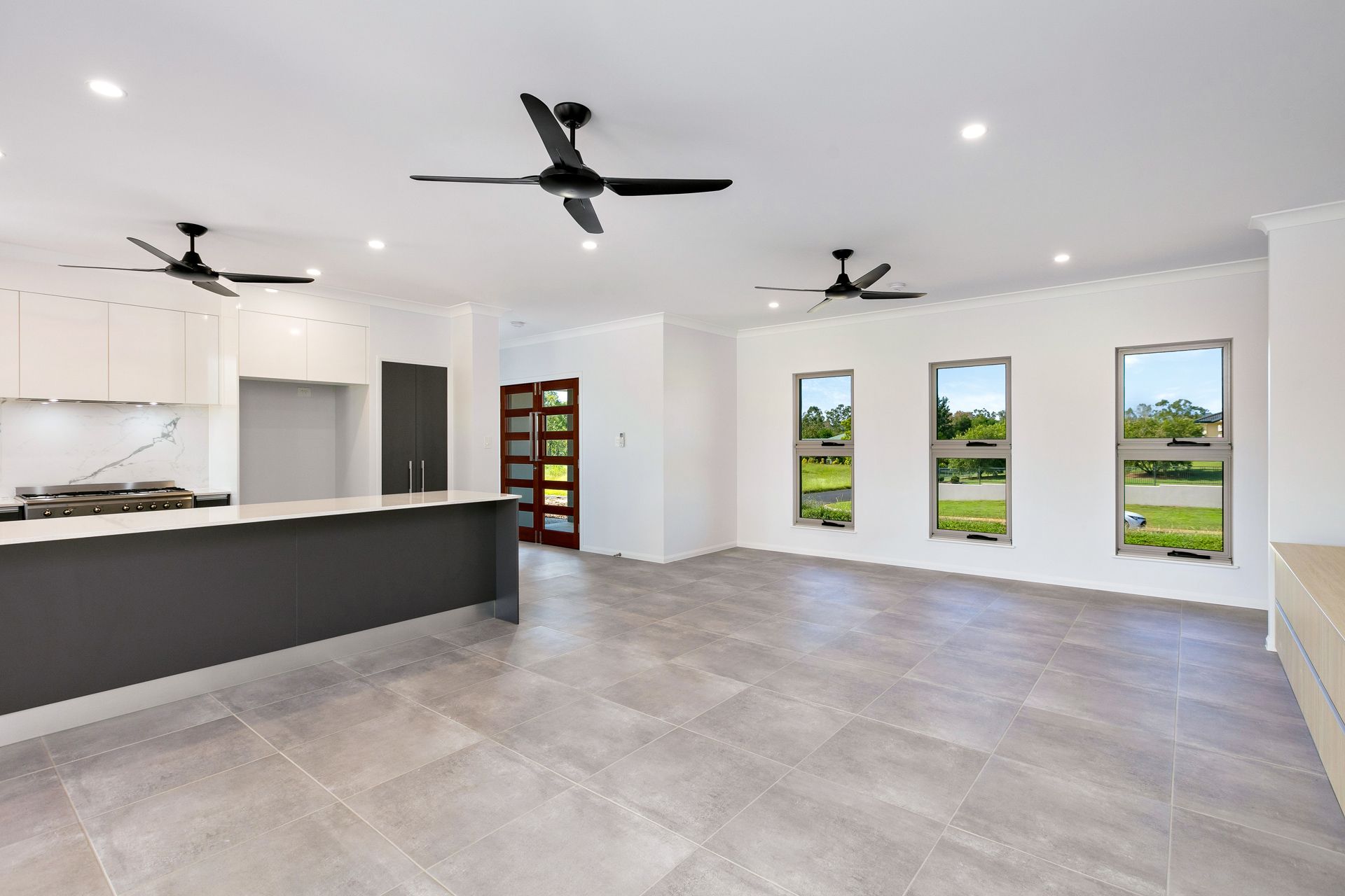 A Modern Kitchen and Dining Area Featuring a Grey Island Counter — Ashlee Jones Homes in Gordonvale, QLD