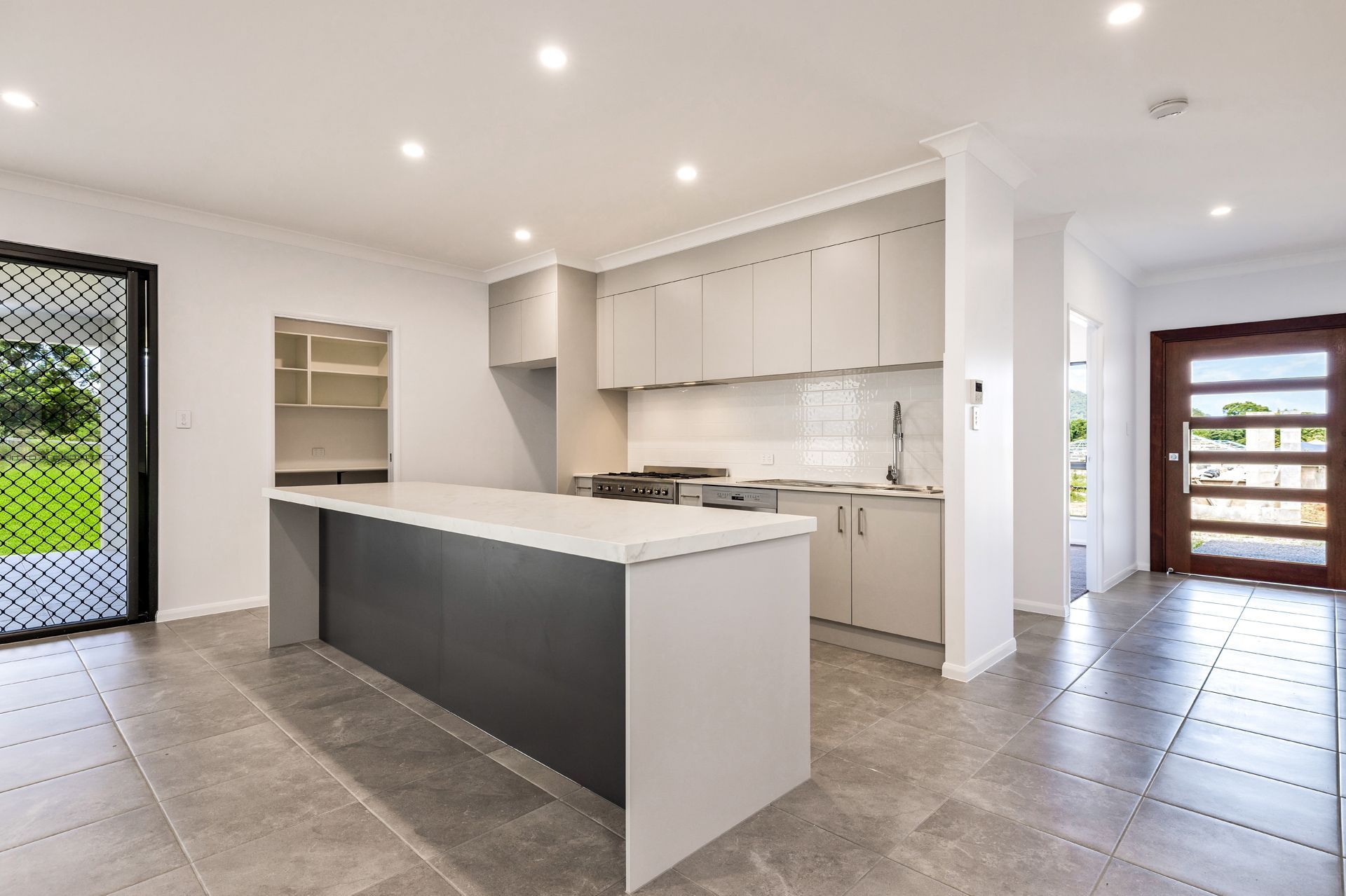 A Modern Kitchen Featuring a Dark Grey Kitchen Island — Ashlee Jones Homes in Gordonvale, QLD