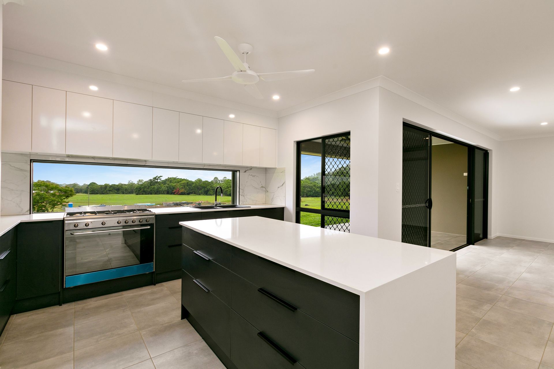 A Modern Kitchen With Dark Cabinets, a White Island — Ashlee Jones Homes in Gordonvale, QLD