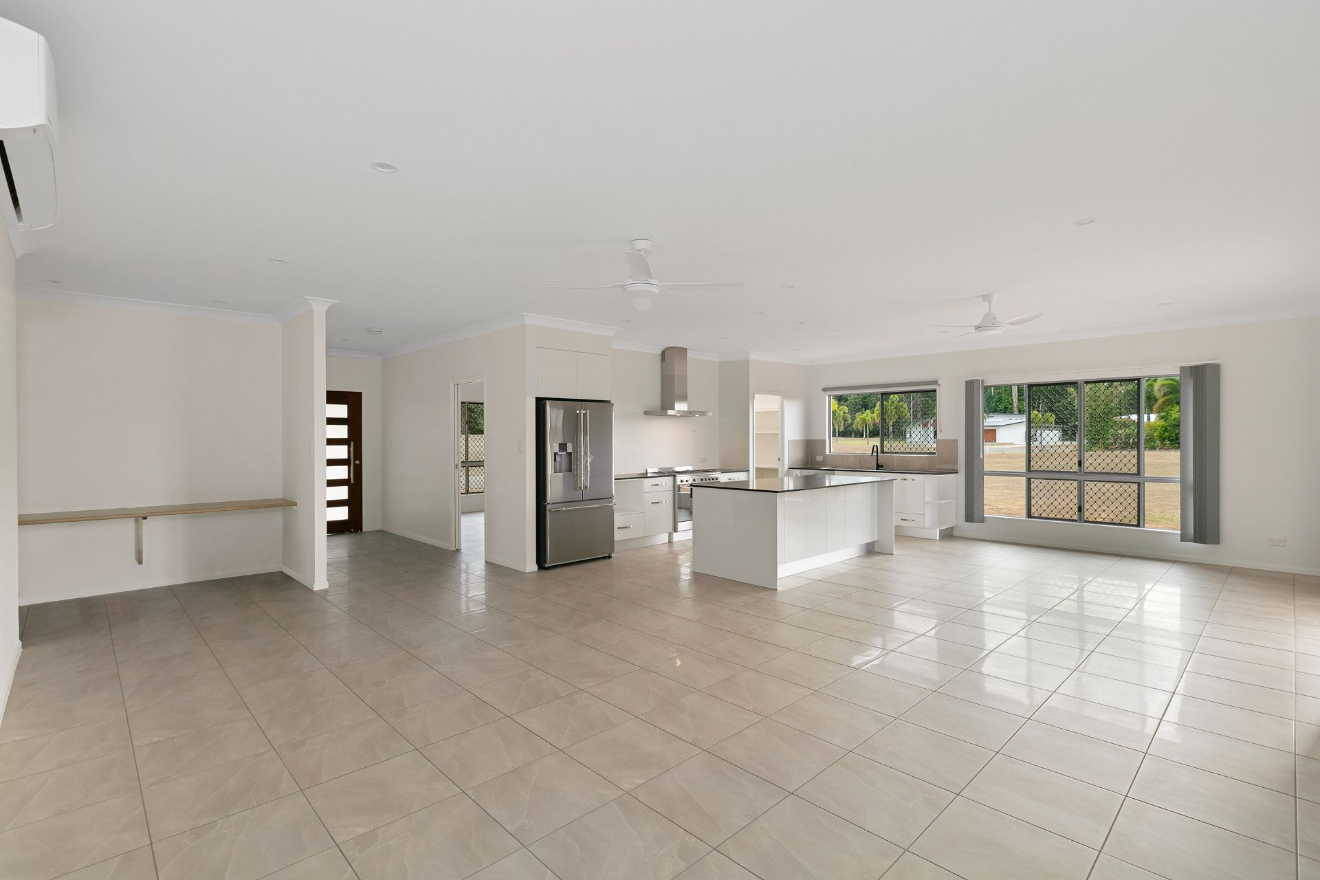 A Bright, Open-plan Living and Kitchen Area With Light-colored Tile Floors — Ashlee Jones Homes in Gordonvale, QLD