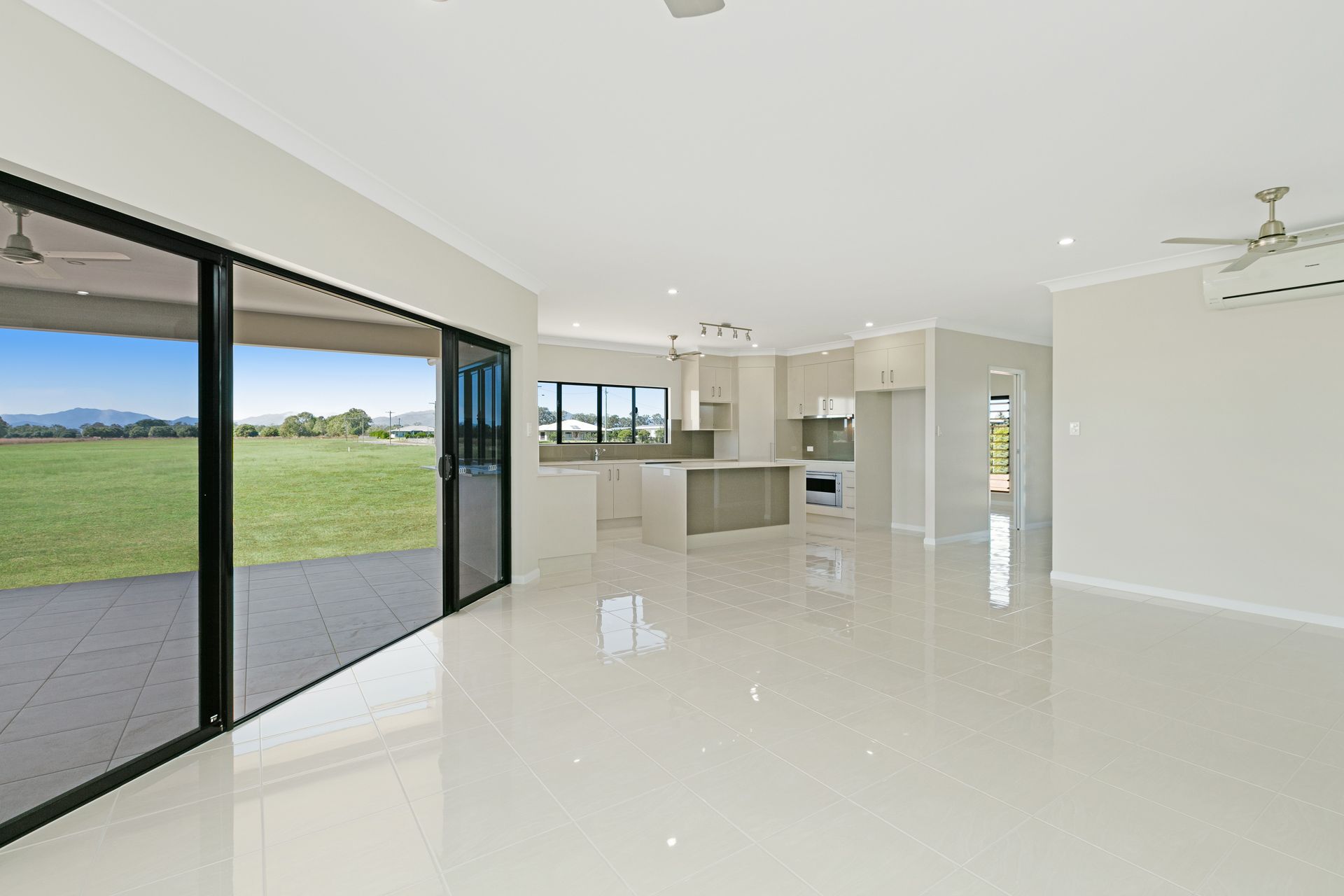 A Spacious, Modern Open-plan Home Interior With White Tile Floors — Ashlee Jones Homes in Gordonvale, QLD