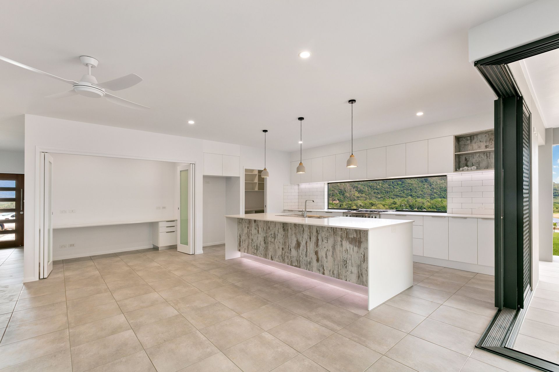 A Modern, Spacious Kitchen Featuring a Textured Stone Island, White Cabinetry — Ashlee Jones Homes in Gordonvale, QLD