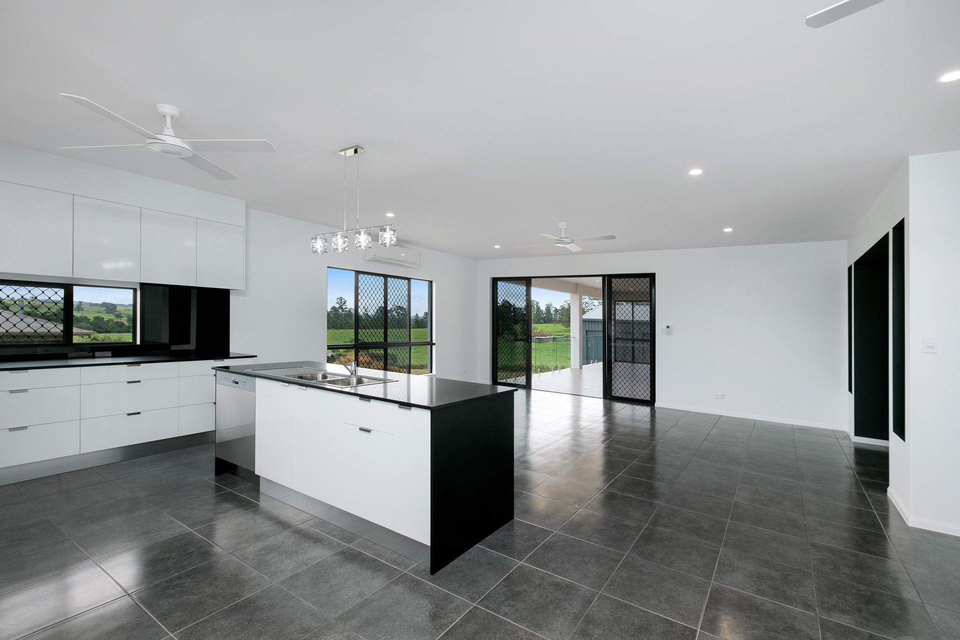 A Modern Kitchen With White Cabinets, a Black Kitchen Island — Ashlee Jones Homes in Gordonvale, QLD