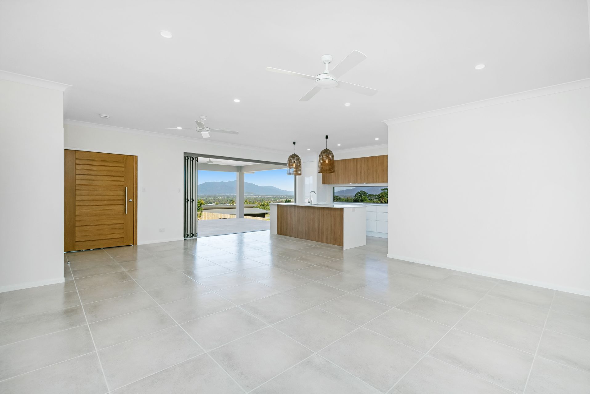 A Bright, Modern Open-plan Kitchen and Living Area With Light Tile Floors — Ashlee Jones Homes in Gordonvale, QLD