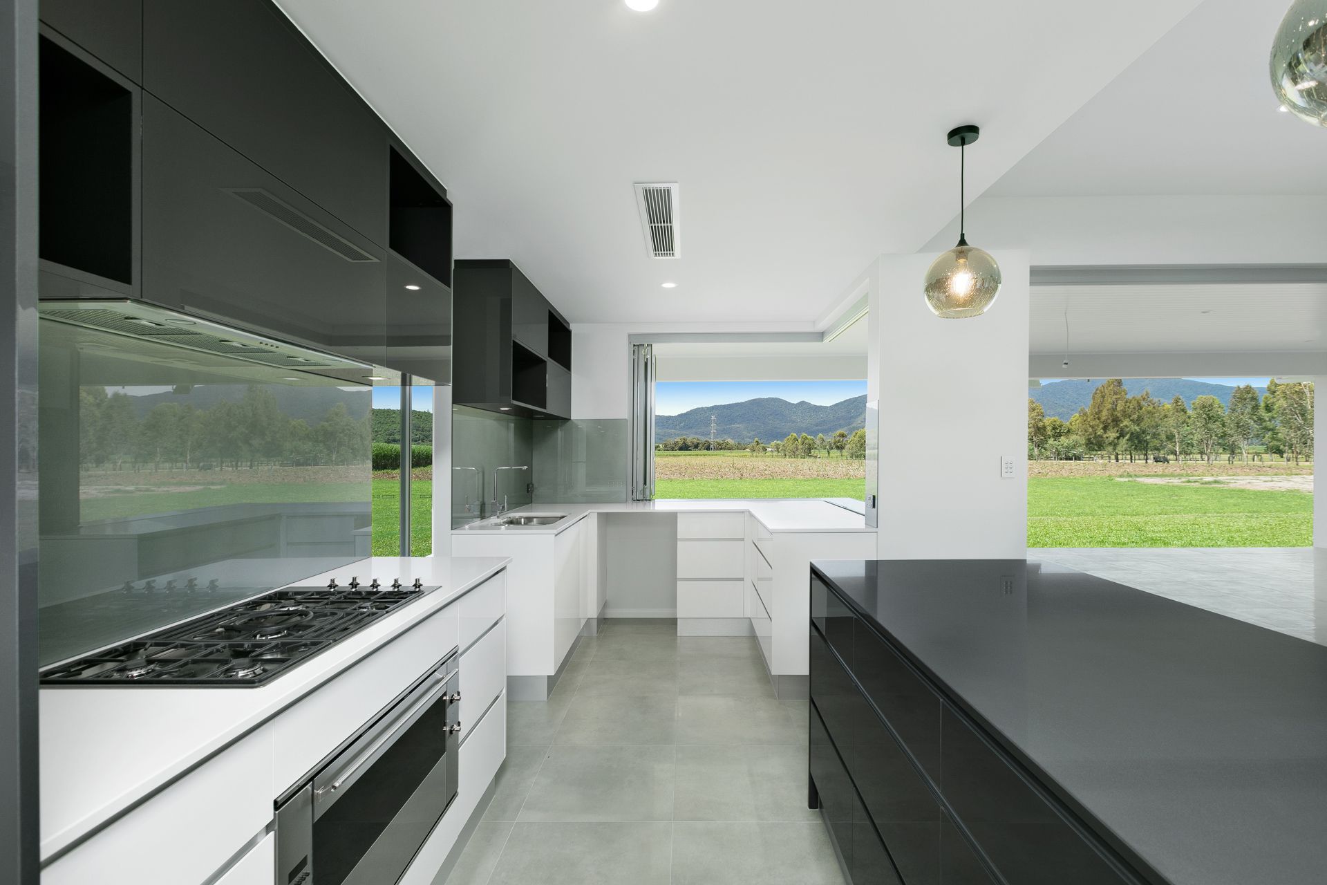 A Modern Kitchen With Black Cabinets and White Countertops — Ashlee Jones Homes in Gordonvale, QLD