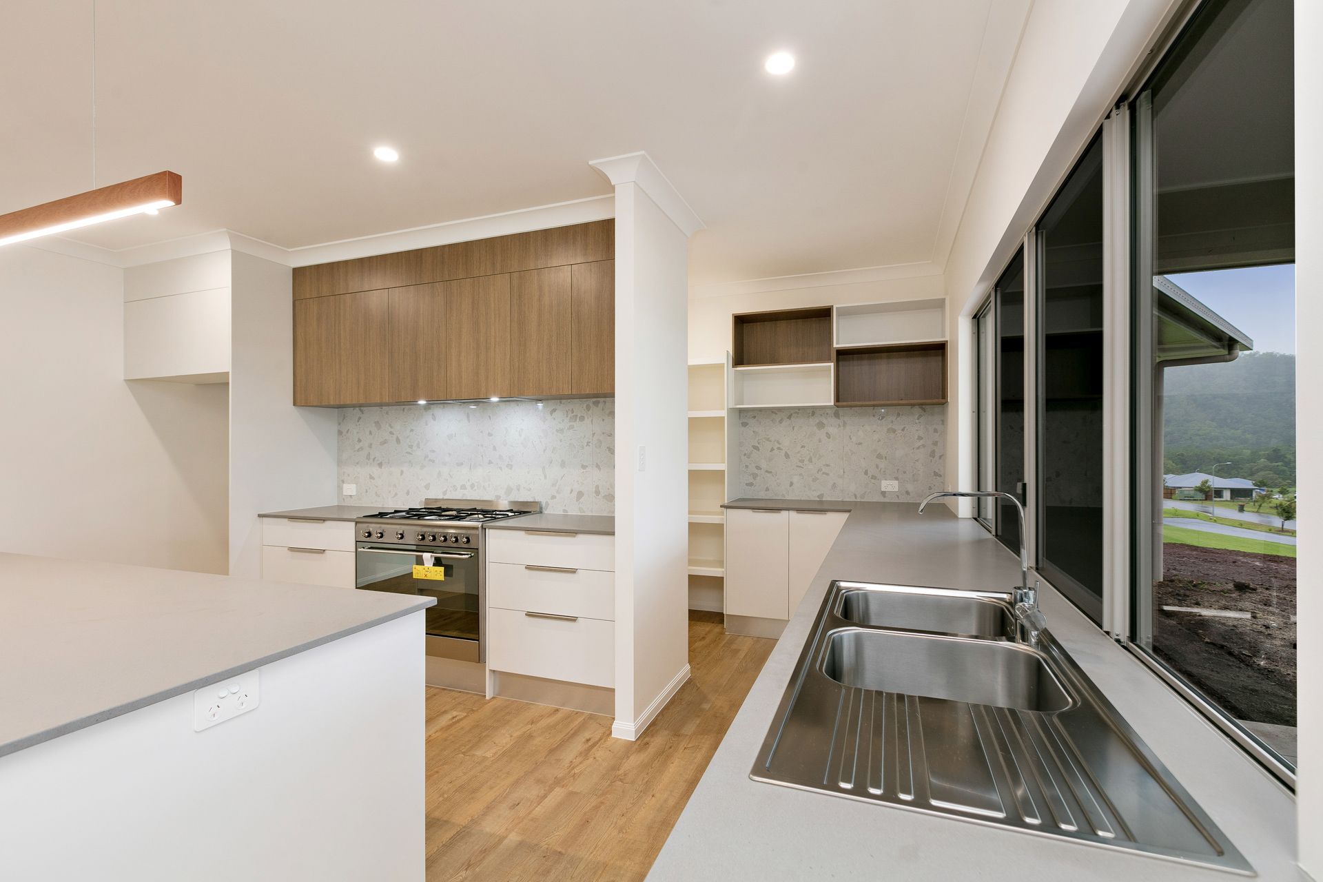 Modern Kitchen With Light Countertops, Wood Cabinets — Ashlee Jones Homes in Gordonvale, QLD