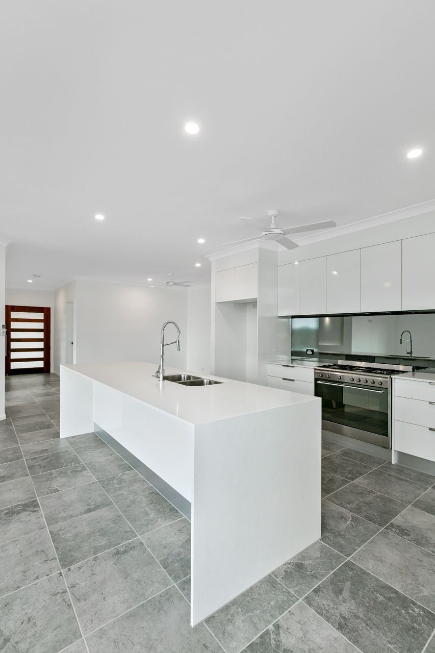 A Bright, Modern Kitchen Featuring a White Island — Ashlee Jones Homes in Gordonvale, QLD
