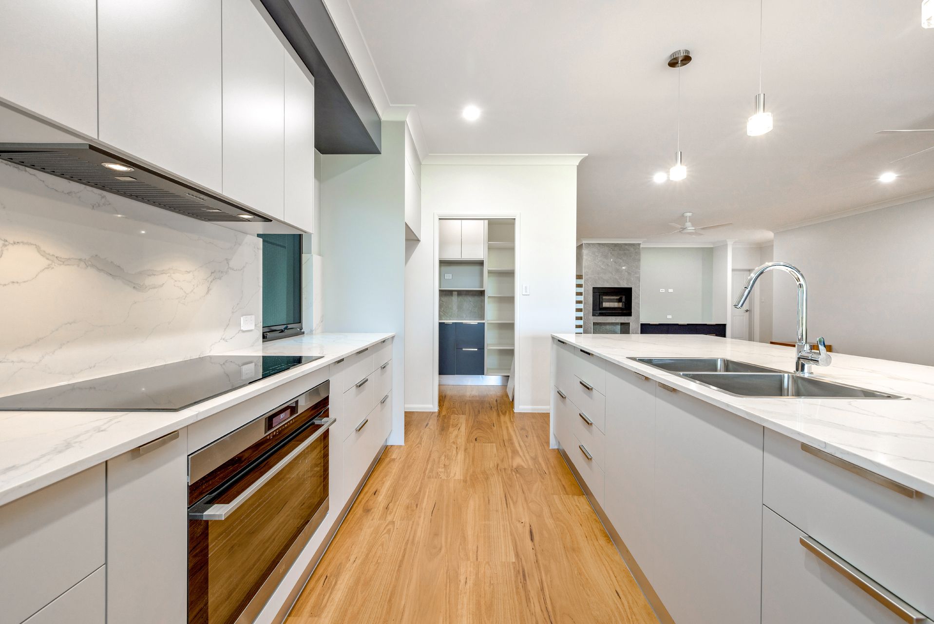 A Modern Kitchen With White Cabinets, Light Wood Flooring — Ashlee Jones Homes in Gordonvale, QLD