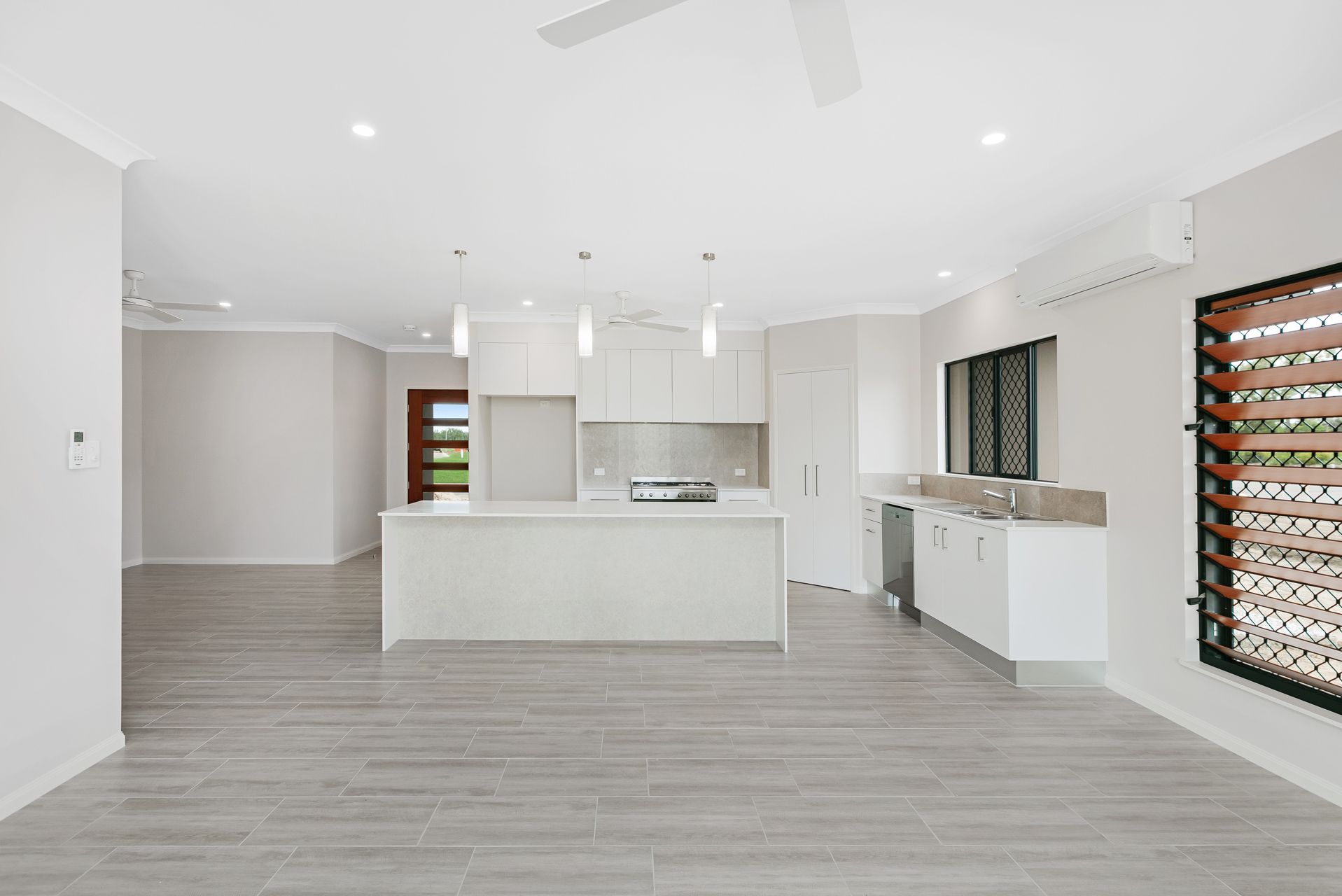 A Modern, Open-plan Kitchen With White Cabinetry, a Central Island — Ashlee Jones Homes in Gordonvale, QLD