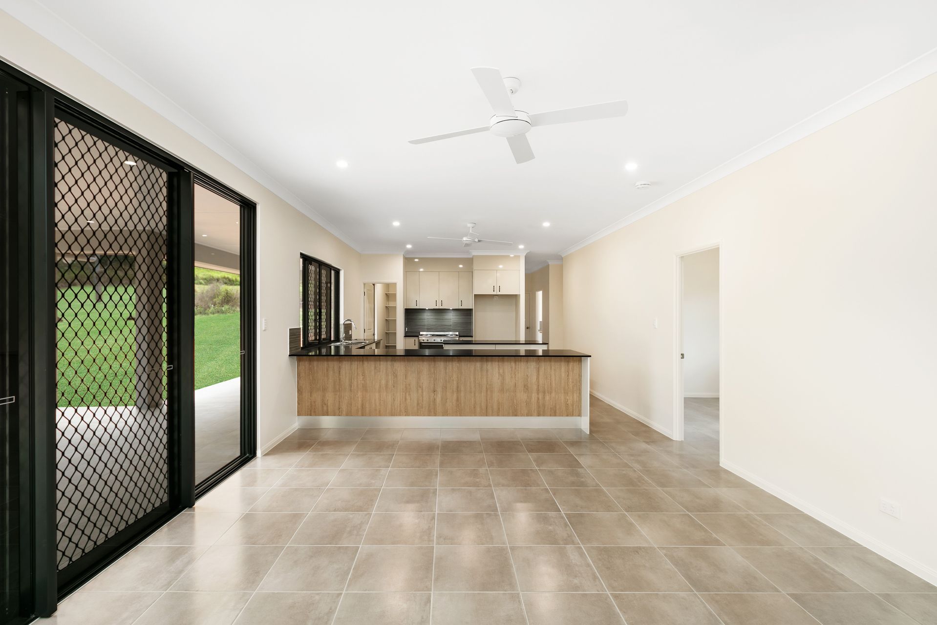 An Open-plan Living Area With Tiled Floors, a Kitchen Island — Ashlee Jones Homes in Gordonvale, QLD