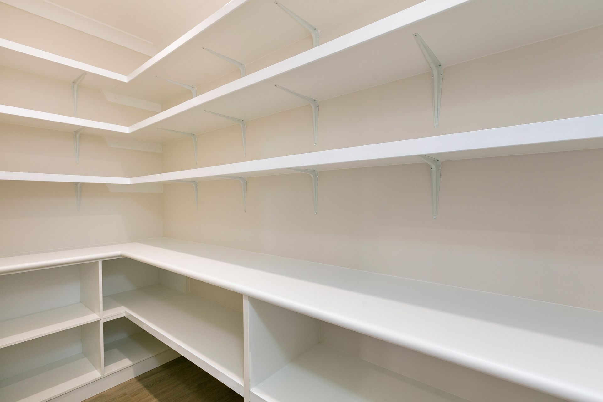 Empty Walk-in Pantry With White L-shaped Shelves and Walls — Ashlee Jones Homes in Gordonvale, QLD