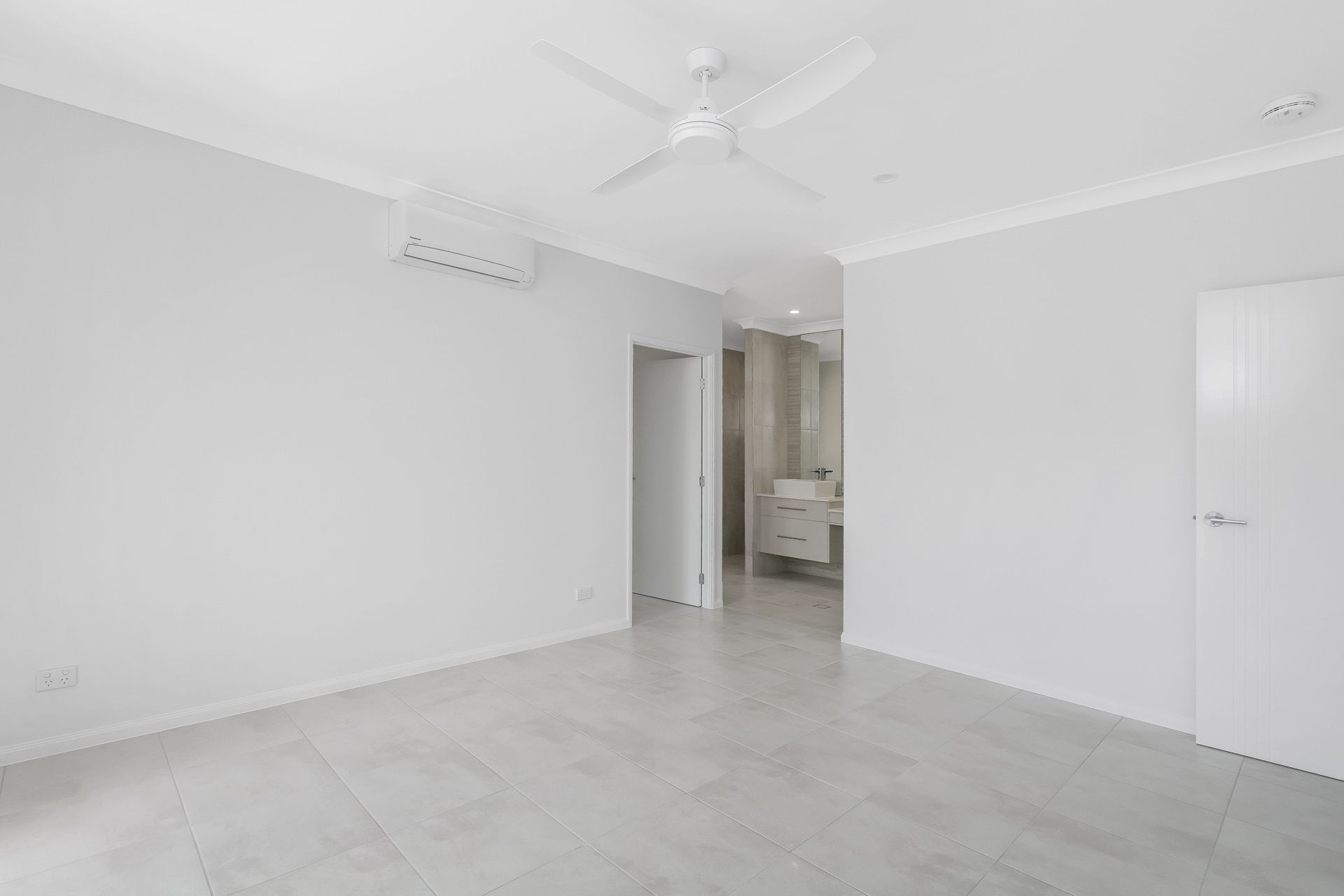 A Bright, Empty Room With Light Grey Tiled Floors — Ashlee Jones Homes in Gordonvale, QLD