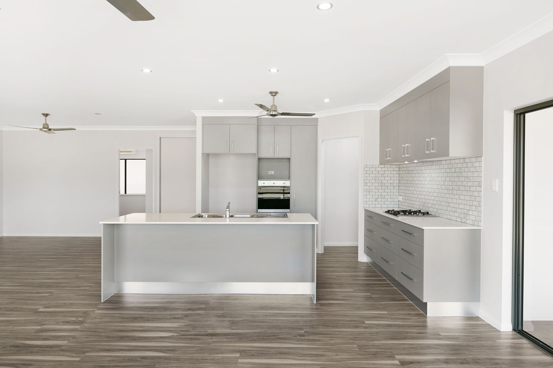A Modern, Open-plan Kitchen With Light Gray Cabinets — Ashlee Jones Homes in Gordonvale, QLD