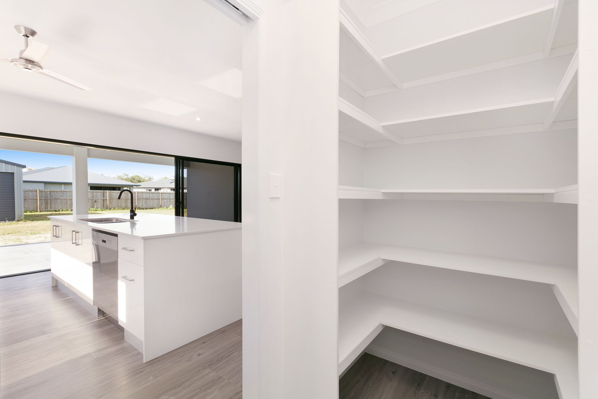A Modern, White Walk-in Pantry With Wrap-around Shelves — Ashlee Jones Homes in Gordonvale, QLD