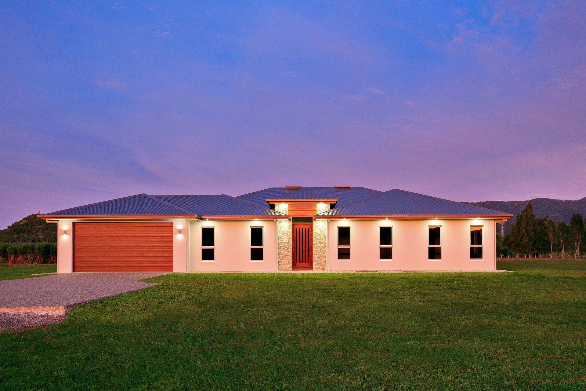 A Wide, Single-story Light-colored House With a Red Garage Door — Ashlee Jones Homes in Gordonvale, QLD