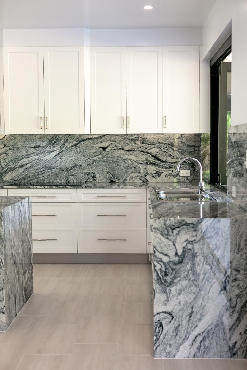 A Kitchen With Granite Counter Tops and White Cabinets — Ashlee Jones Homes in Gordonvale, QLD