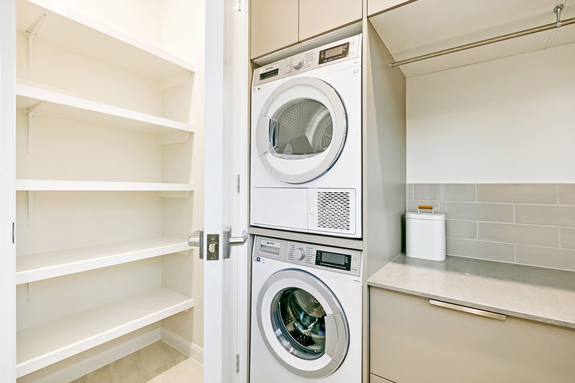 A Laundry Space With White Stacked Washer and Dryer — Ashlee Jones Homes in Gordonvale, QLD