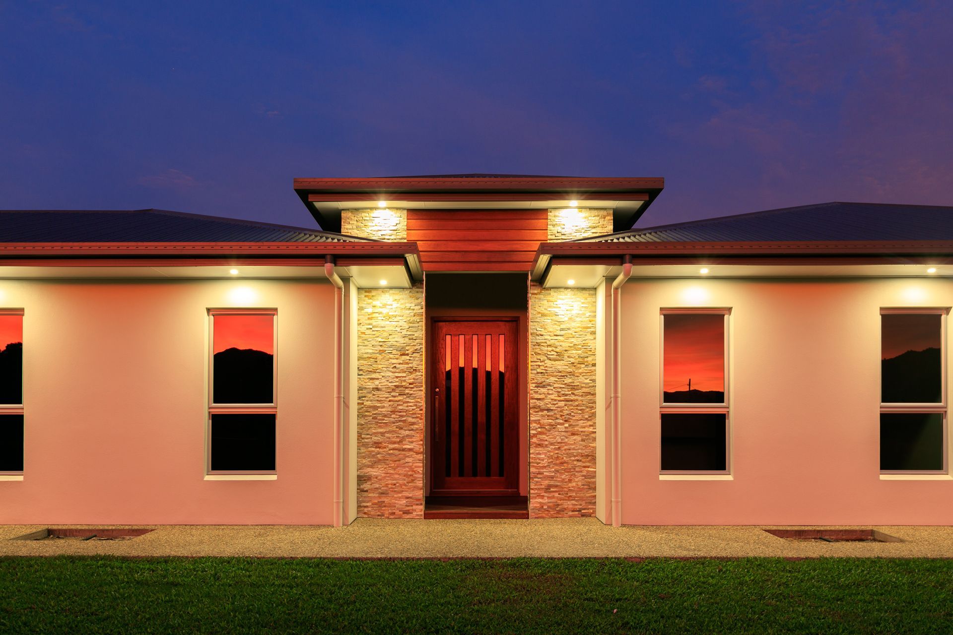 Modern, Symmetrical Single-story Home at Dusk With a Stone-accented Entrance — Ashlee Jones Homes in Gordonvale, QLD