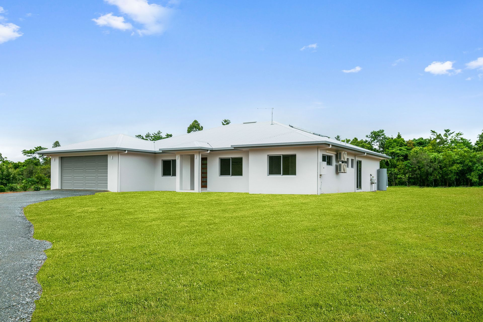 A White, Single-story House With a Grey Garage Door — Ashlee Jones Homes in Gordonvale, QLD
