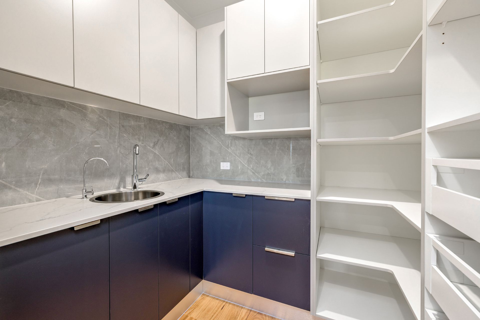A Modern Galley-style Kitchen With Navy Blue Lower Cabinets — Ashlee Jones Homes in Gordonvale, QLD