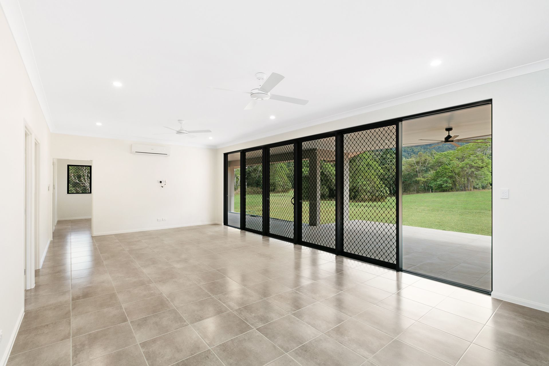 Spacious, Minimalist Room With Beige Tile Floors and White Walls — Ashlee Jones Homes in Gordonvale, QLD