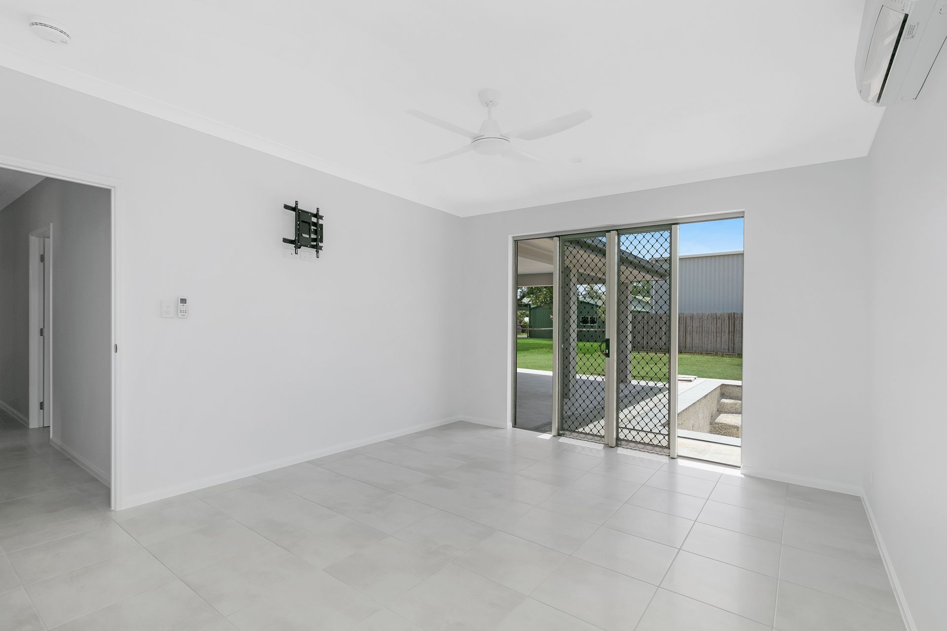 A Bright, Empty Living Room With White Walls, Light Tile Flooring — Ashlee Jones Homes in Gordonvale, QLD
