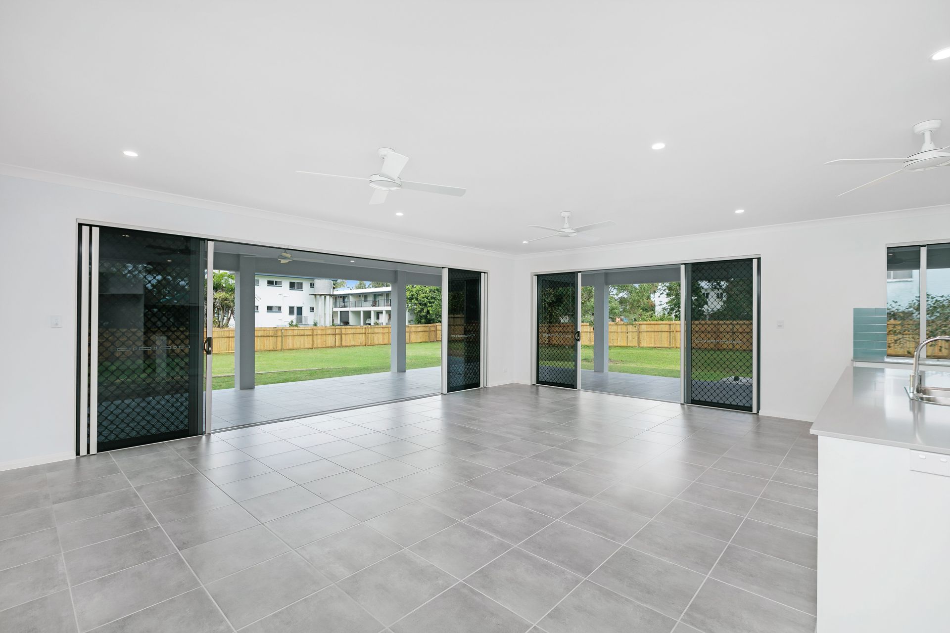 A Bright, Modern Open-plan Living Room With Grey Tiled Floors — Ashlee Jones Homes in Gordonvale, QLD
