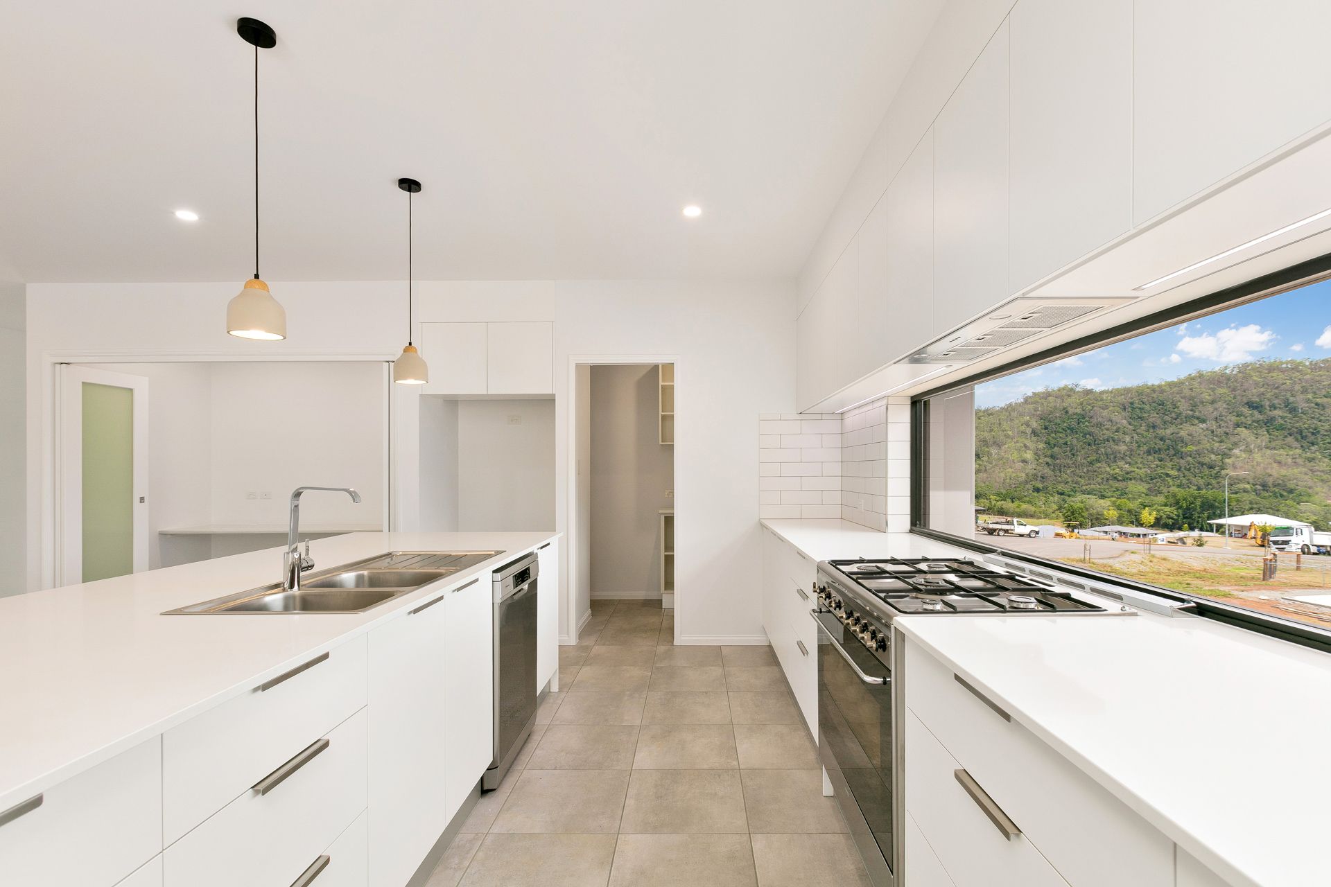 Modern White Kitchen With a Large Island, Stainless Steel Appliances — Ashlee Jones Homes in Gordonvale, QLD
