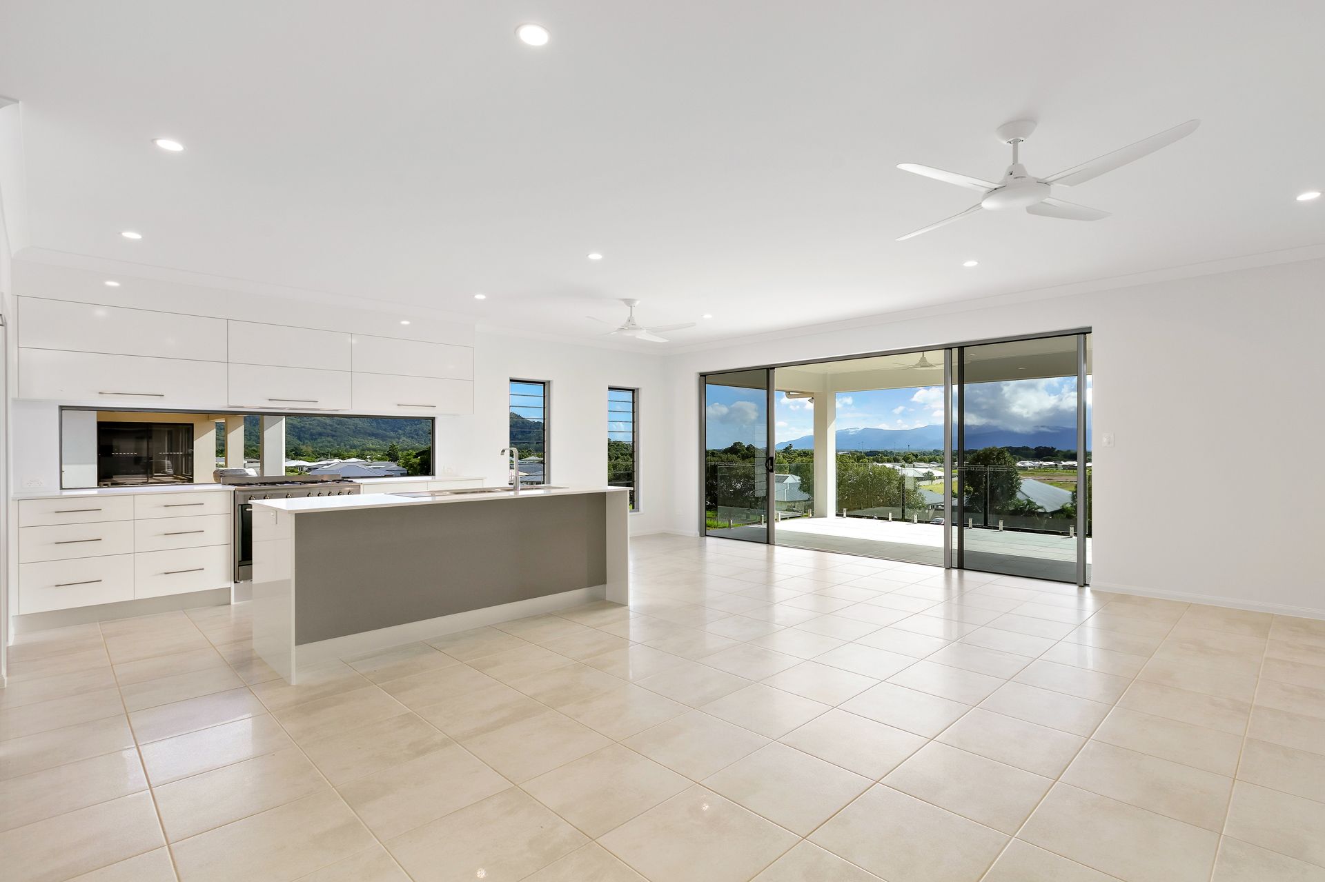 A Bright, Modern Open-plan Kitchen and Living Area With White Cabinets — Ashlee Jones Homes in Gordonvale, QLD