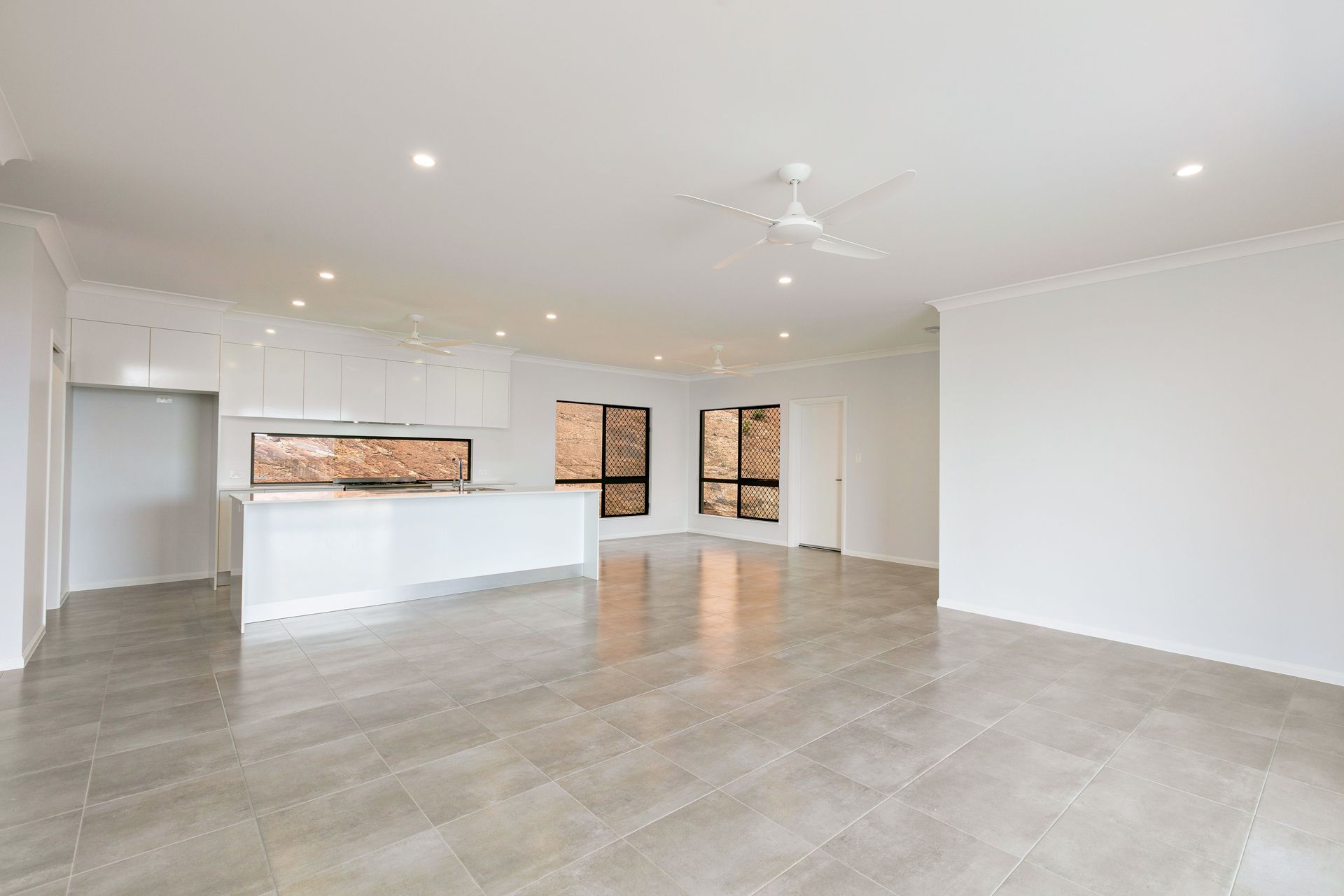 A Bright, Modern Open-plan Kitchen and Living Area With White Cabinetry — Ashlee Jones Homes in Gordonvale, QLD