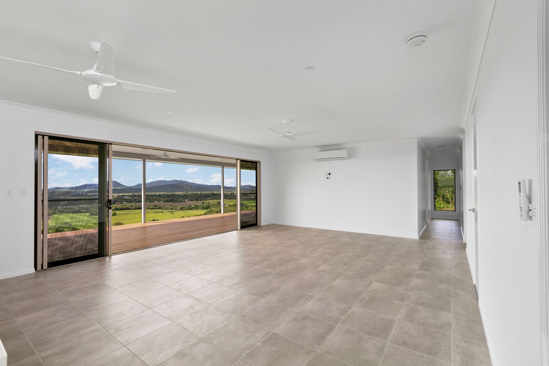 An Empty, Minimalist Living Room With Beige Tile Floors — Ashlee Jones Homes in Gordonvale, QLD
