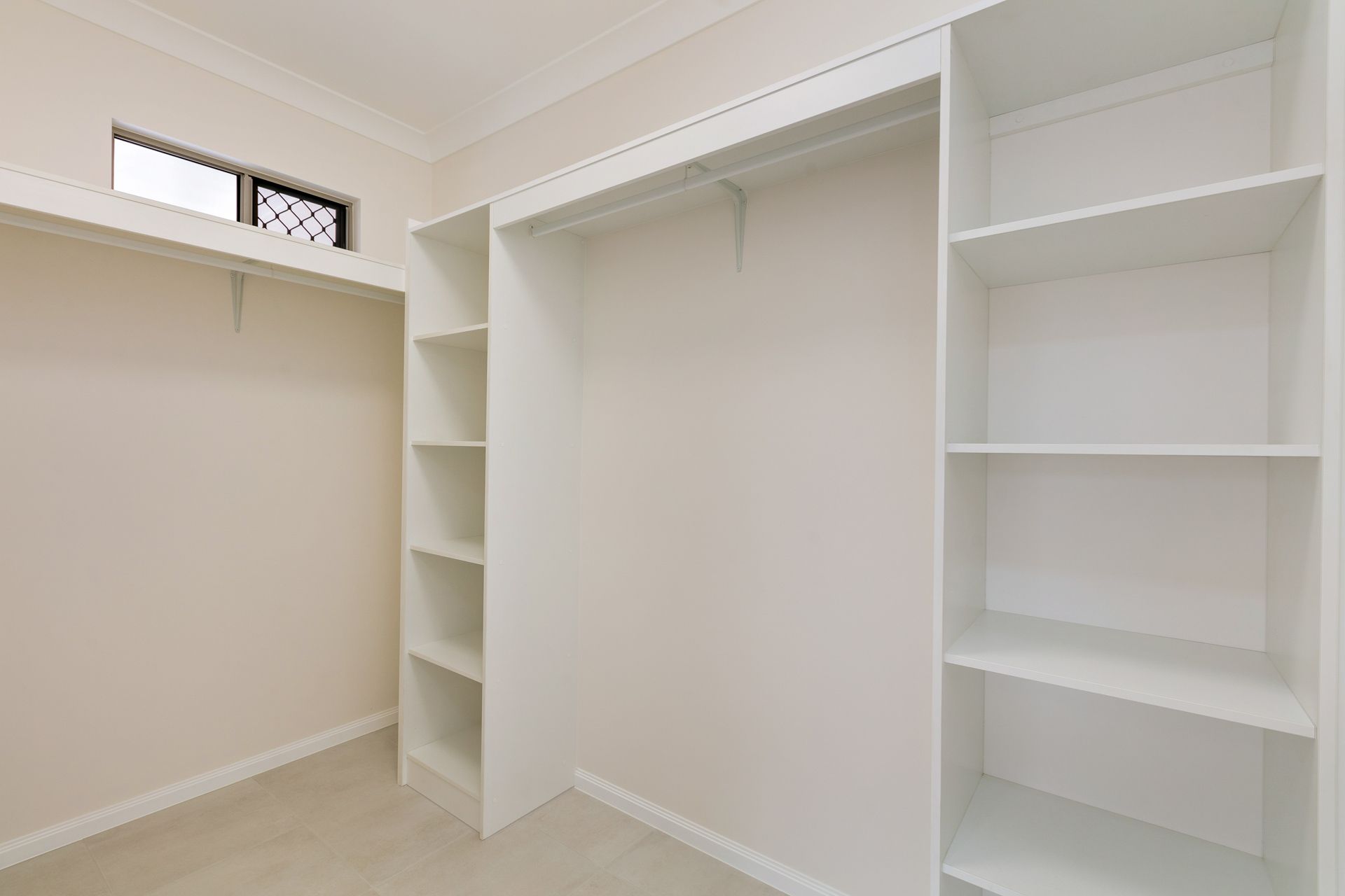 A White, Walk-in Closet With Built-in Shelving Units and a Hanging Rack — Ashlee Jones Homes in Gordonvale, QLD