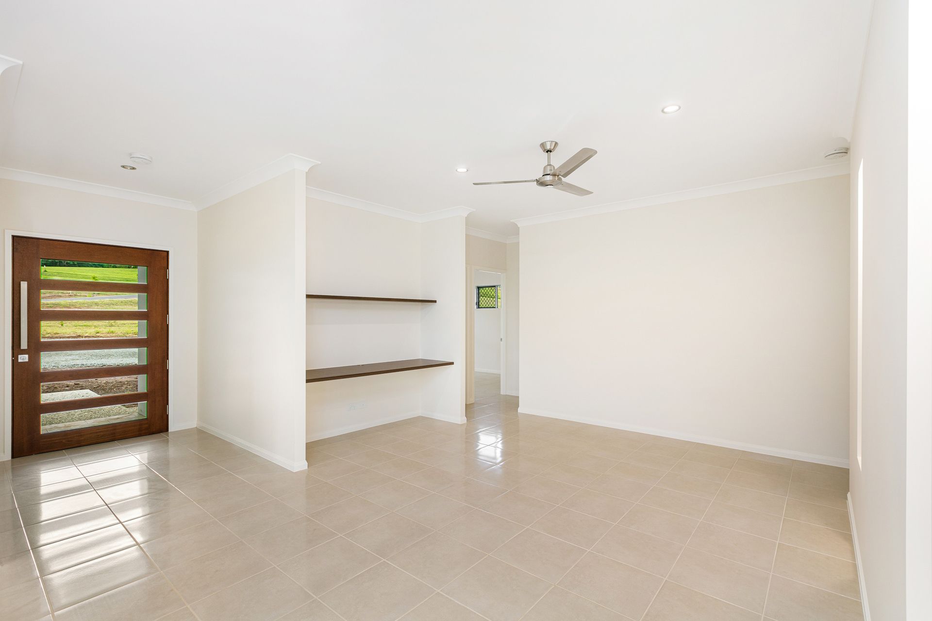 An Empty, Brightly Lit Living Space With Neutral Tile Floors — Ashlee Jones Homes in Gordonvale, QLD