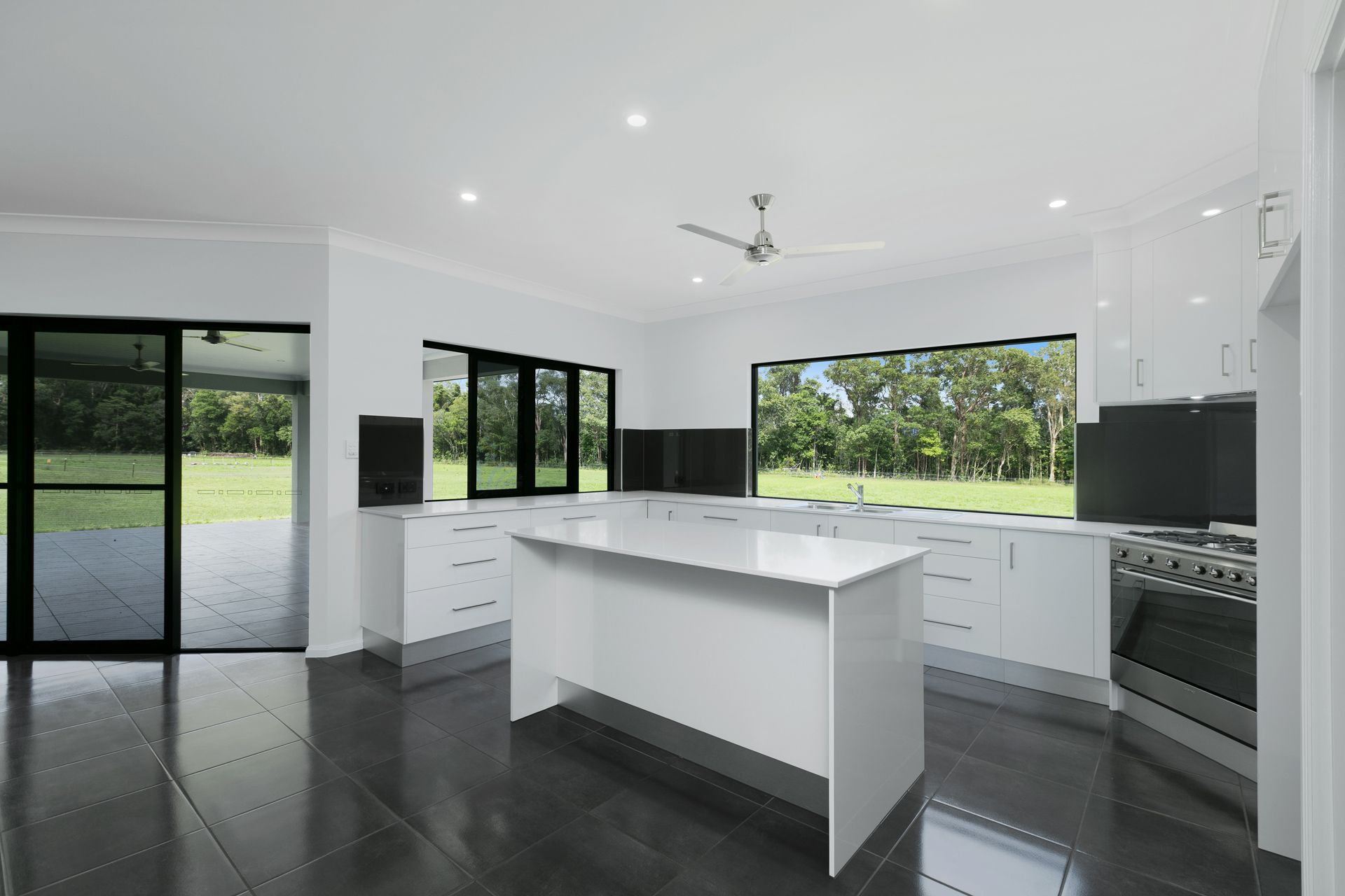 A Modern Kitchen With White Cabinets, a Central Island — Ashlee Jones Homes in Gordonvale, QLD