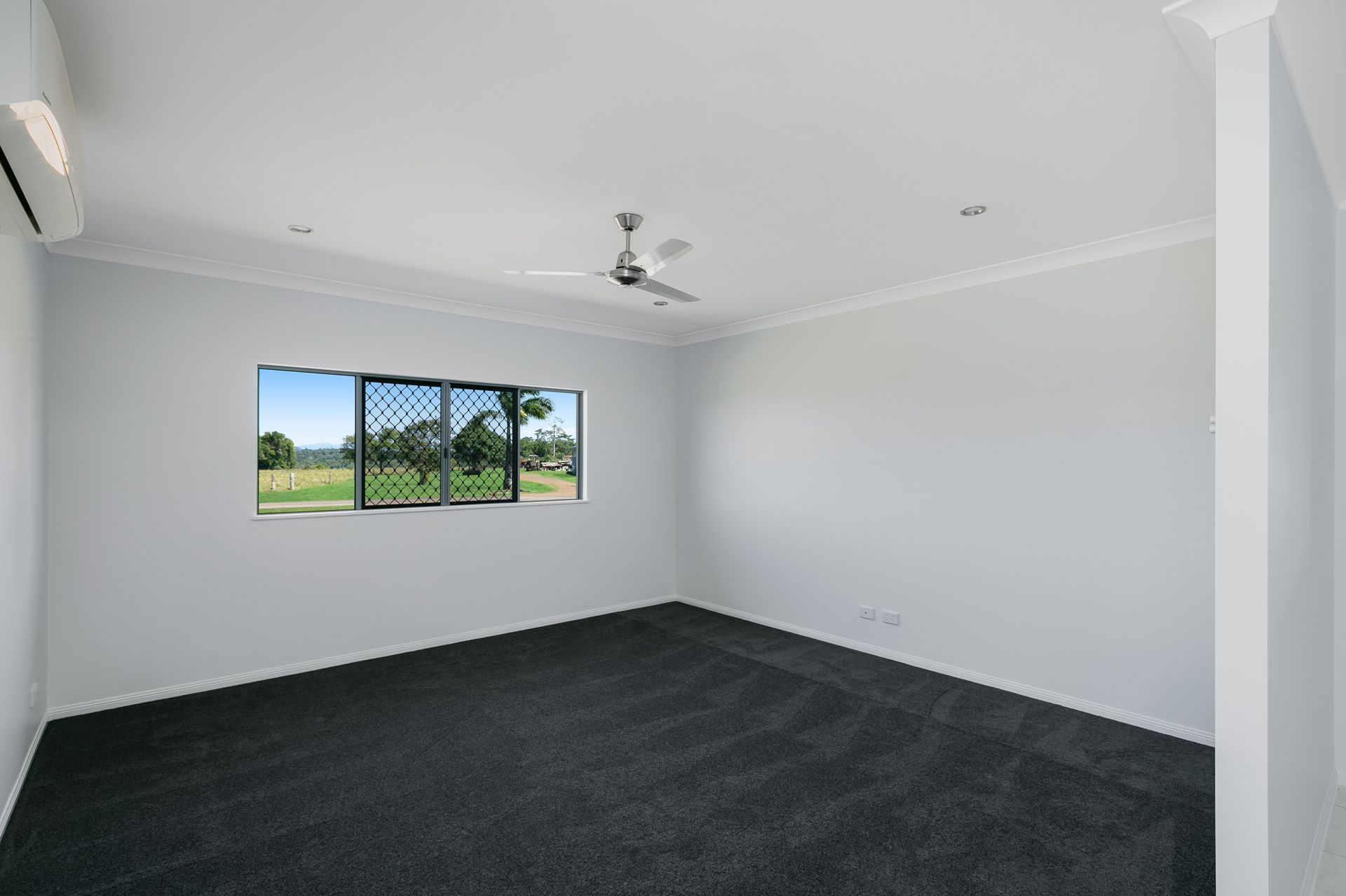 An Empty Bedroom With Light Gray Walls, Dark Gray Carpet — Ashlee Jones Homes in Gordonvale, QLD