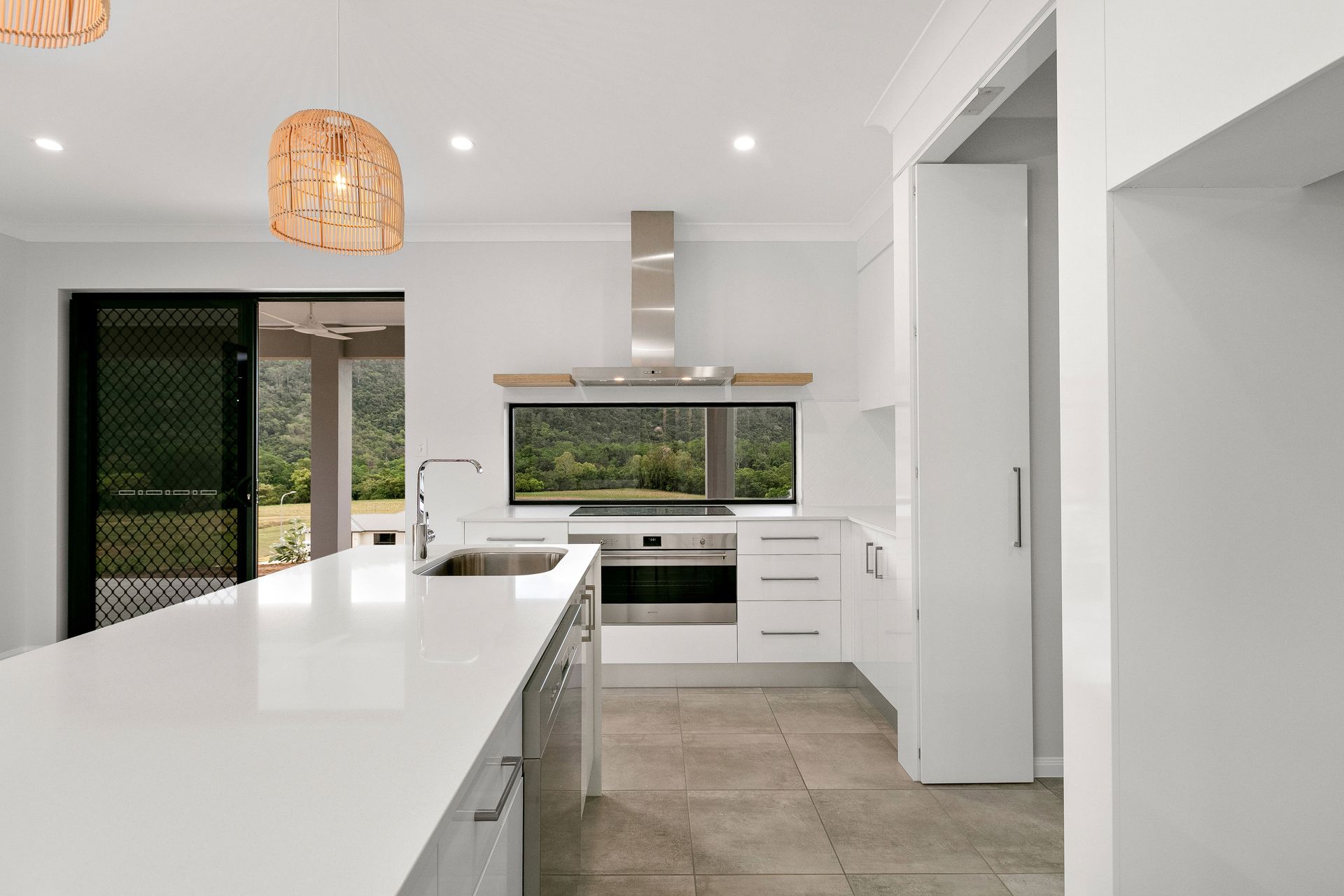 Modern Kitchen Featuring a White Island, Stainless Steel Range Hood — Ashlee Jones Homes in Gordonvale, QLD